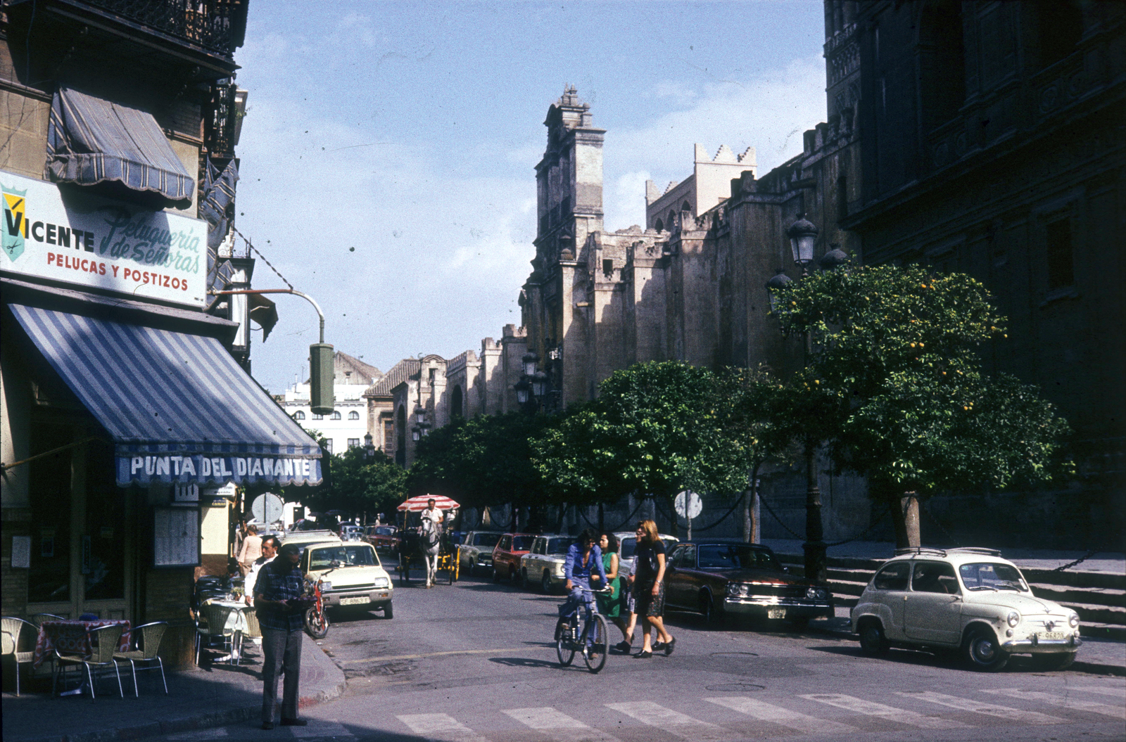 Spanyolország, Sevilla, Calle Alemanes az Avenida de la Constitución felől, szemben a katedrális kertjének (Patio de los Naranjos) bejárata., 1974, Ormos Imre Alapítvány, dr  Dalányi László, színes, napellenző, gyalogátkelő, kerékpár, Fortepan #100567