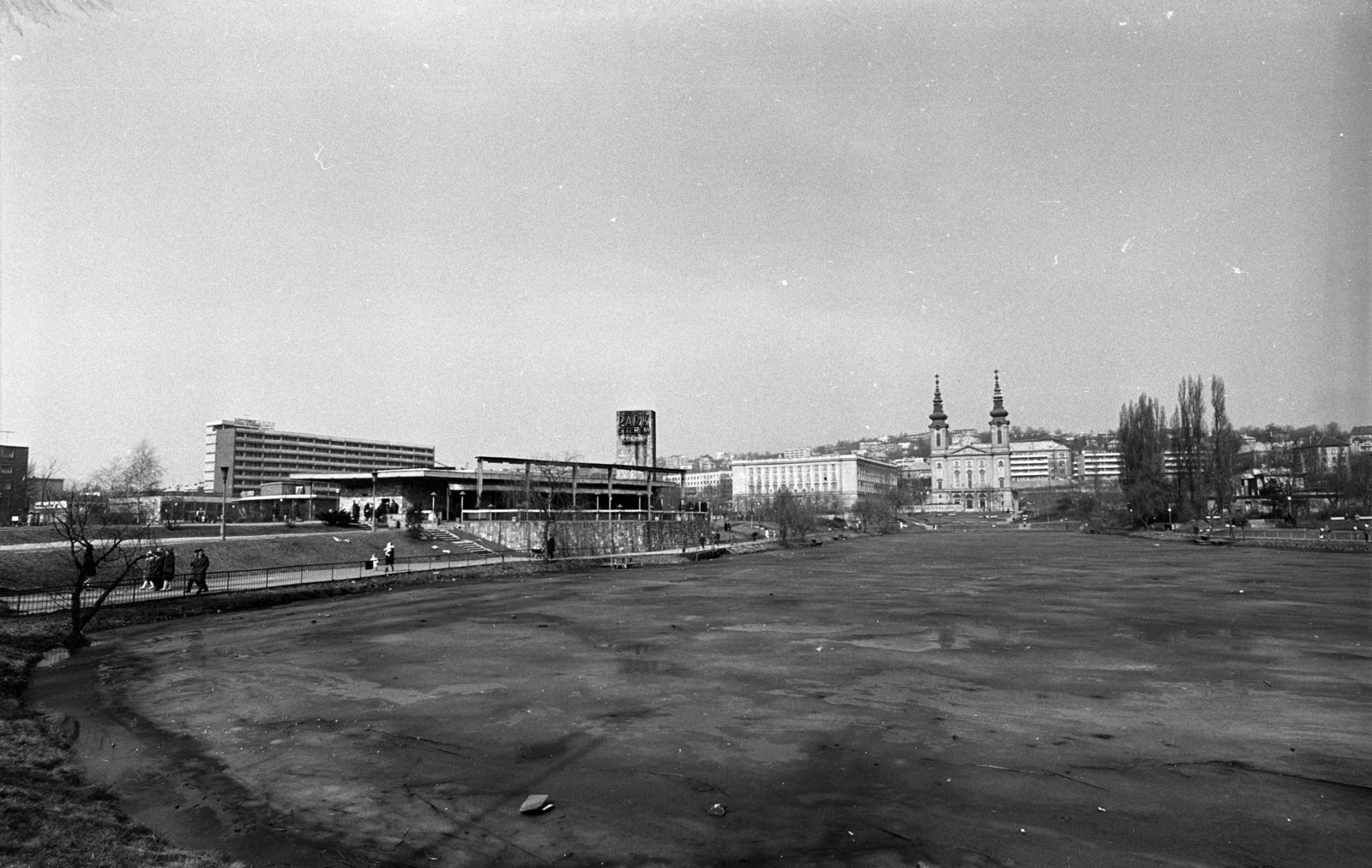 Magyarország, Budapest XI., a Feneketlen tó partján a Park étterem, mögötte balra a Sport (később Flamenco) szálló. Szemben a József Attila (később Budai Ciszterci Szent Imre) Gimnázium és a Szent Imre templom, 1969, Erdei Katalin, tél, templom, gimnázium, neon felirat, Budapest, ciszterci rend, neobarokk stílus, Wälder Gyula-terv, Fortepan #100899