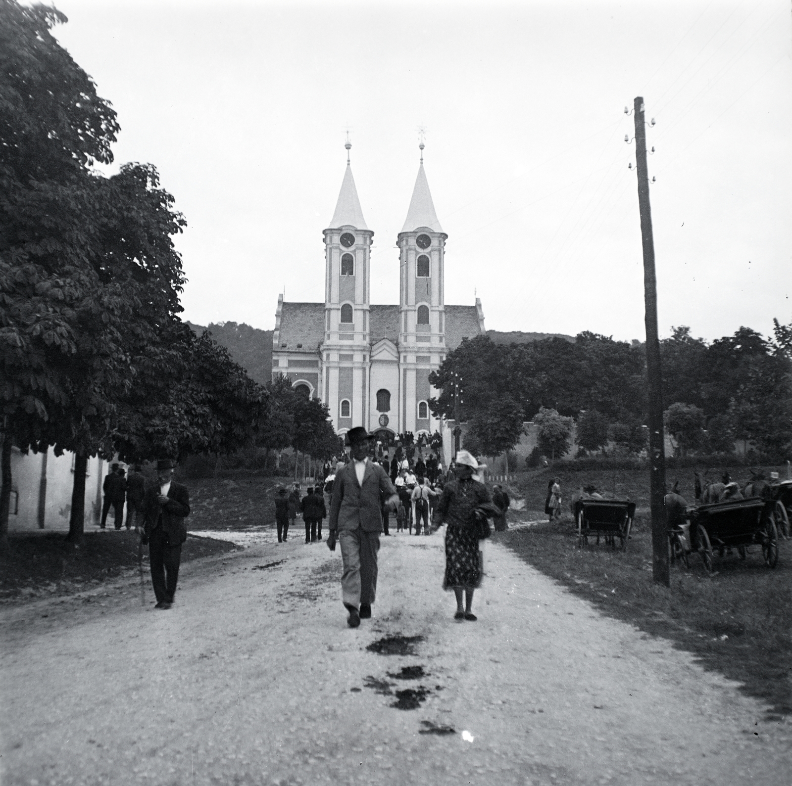 Hungary, untitled, Siklós, (ekkor önálló, ma a város része), Járó Péter utca, távolban a kegytemplom., 1943, Kurutz Márton, church, Horse-drawn carriage, pylon, aerial wire, village fair, pilgrimage, chestnut tree, Franciscans, sokác folk costume, Fortepan #10253