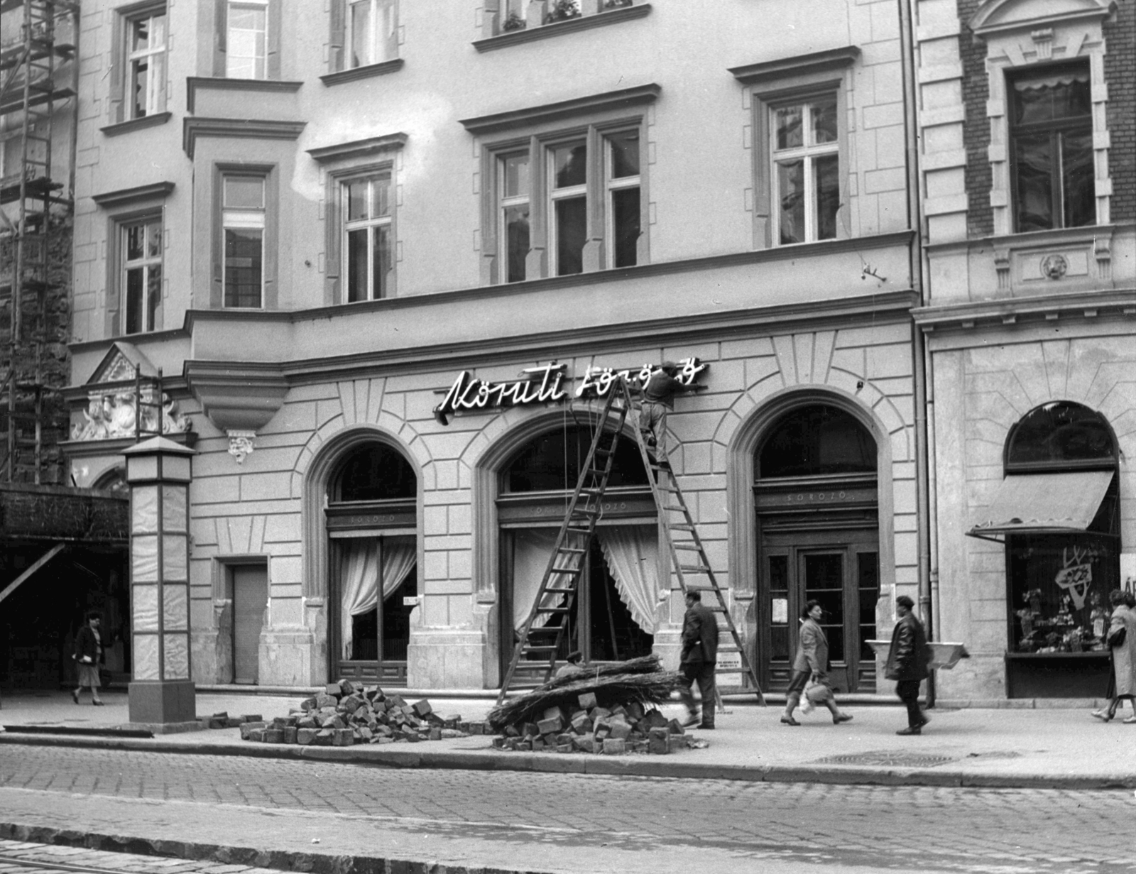 Hungary, Budapest VIII., József körút 85., Körúti söröző. A kép forrását kérjük így adja meg: Fortepan / Budapest Főváros Levéltára. Levéltári jelzet: HU_BFL_XV_19_c_11, 1958, Budapest Főváros Levéltára / Városrendezési és Építészeti Osztályának fényképei, A Fővárosi Tanács VB Városrendezési és Építészeti Osztályának, pedestrian, street view, genre painting, ad pillar, ladder, cobblestones, scaffolding, safety island, Budapest, Fortepan #103541