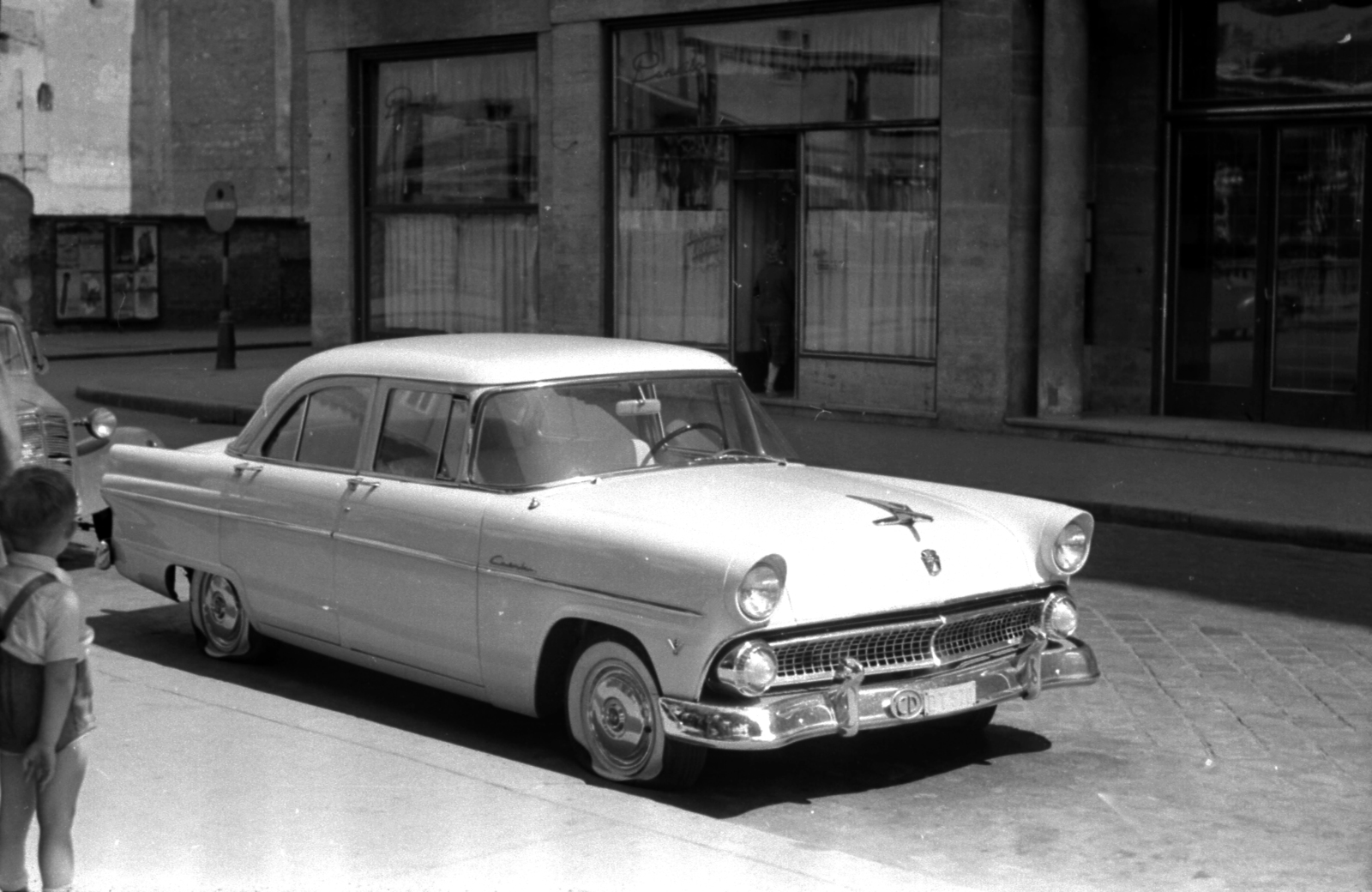 Hungary, Budapest V., Petőfi tér, háttérben a Régi posta utca torkolata. 1955-ös Ford Customline személygépkocsi. A kép forrását kérjük így adja meg: Fortepan / Budapest Főváros Levéltára. Levéltári jelzet: HU.BFL.XV.19.c.10, 1956, Budapest Főváros Levéltára / BRFK helyszínelési fényképei, BRFK Hivatala Bűnügyi Technikai Osztály, american brand, Ford-brand, cobblestones, road sign, flat tyre, Budapest, diplomatic sign, Fortepan #103900