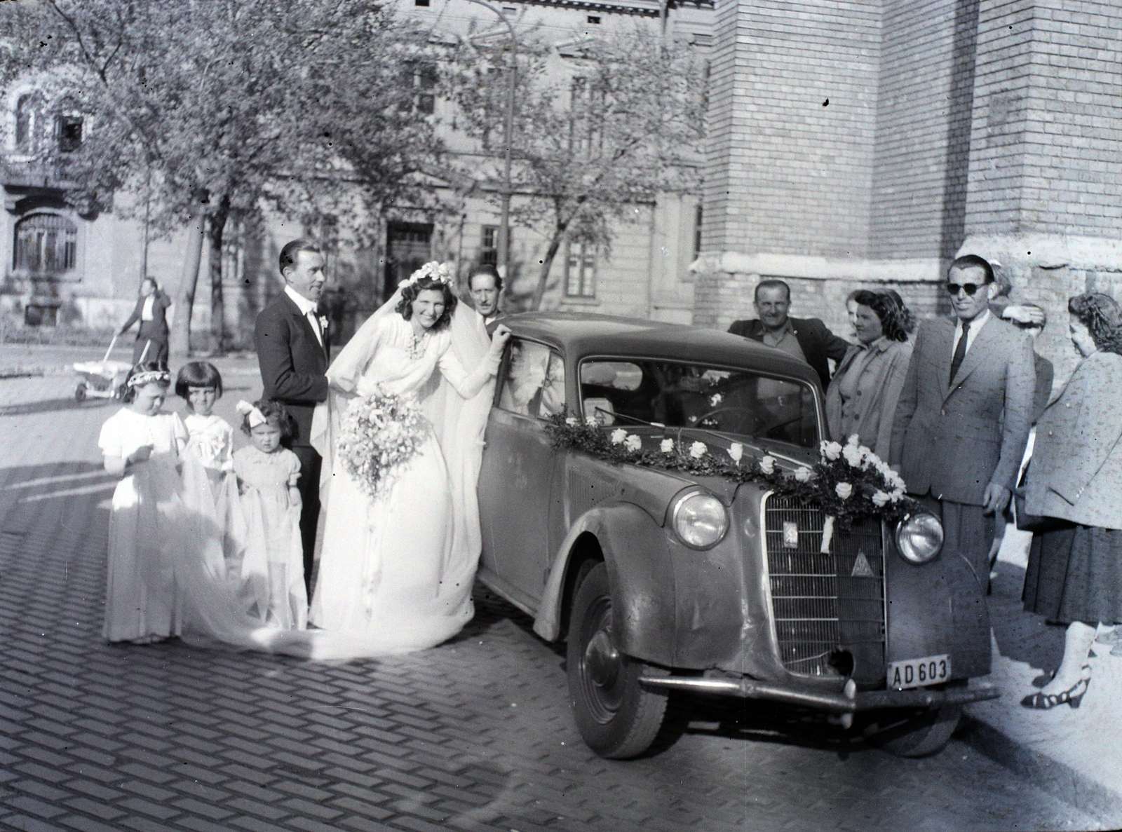 Magyarország, Budapest VII., Rózsák tere a templom előtt., 1948, Hámori Gyula, esküvő, német gyártmány, Opel-márka, menyasszony, automobil, rendszám, Opel Olympia 1935, Budapest, nyoszolyólány, autóba szállás, napszemüveg, koszorúslány, virágdíszítés, Fortepan #105176