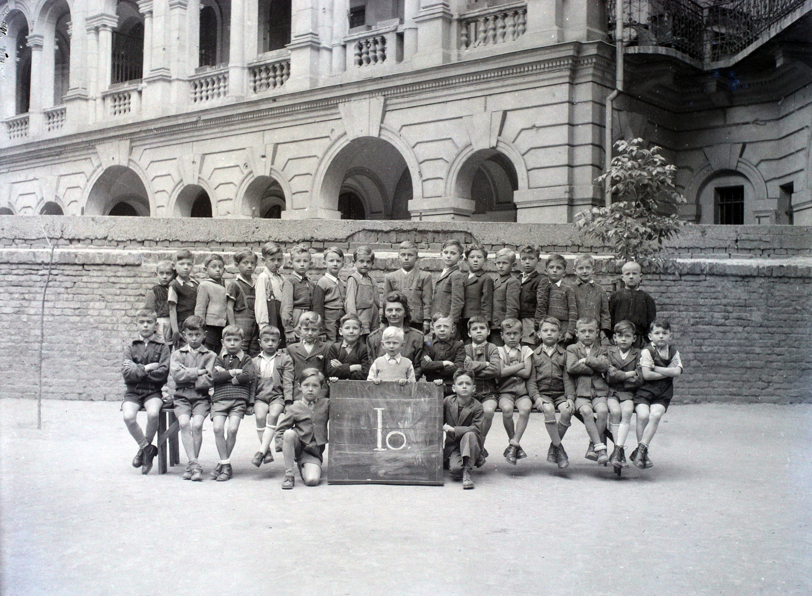Hungary, Budapest VI., Felső erdősori Általános iskola (később Erkel Ferenc Általános Iskola) udvara, csoportkép egy elsős osztályról. Háttérben az Andrássy út 83–85. számú ház udvari homlokzata., 1948, Hámori Gyula, Budapest, class photo, Fortepan #105240