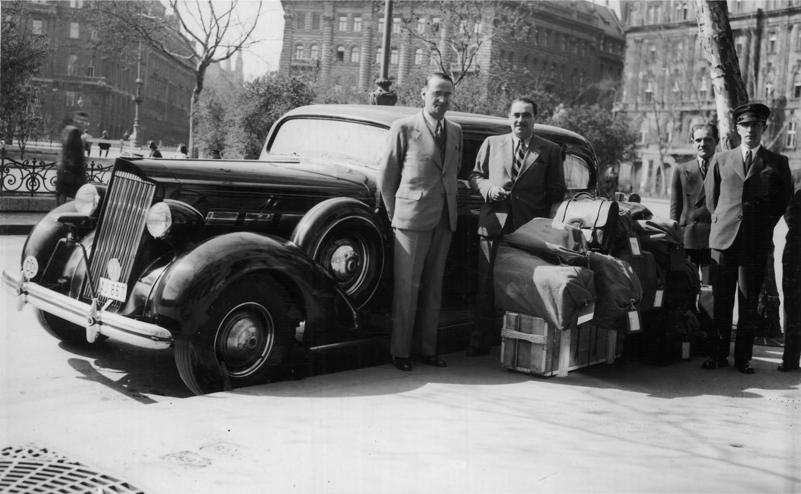 Magyarország, Budapest V., Szabadság tér, előtérben balra Carl Lutz svájci diplomata. Háttérben balra a Vécsey utca, jobbra a Honvéd utca., 1942, Archiv für Zeitgeschichte ETH Zürich / Agnes Hirschi, Carl Lutz, amerikai gyártmány, sofőr, rendszám, Packard-márka, Packard 120, pótkerék, Budapest, poggyász, sofőrsapka, diplomata jelzés, Fortepan #105657