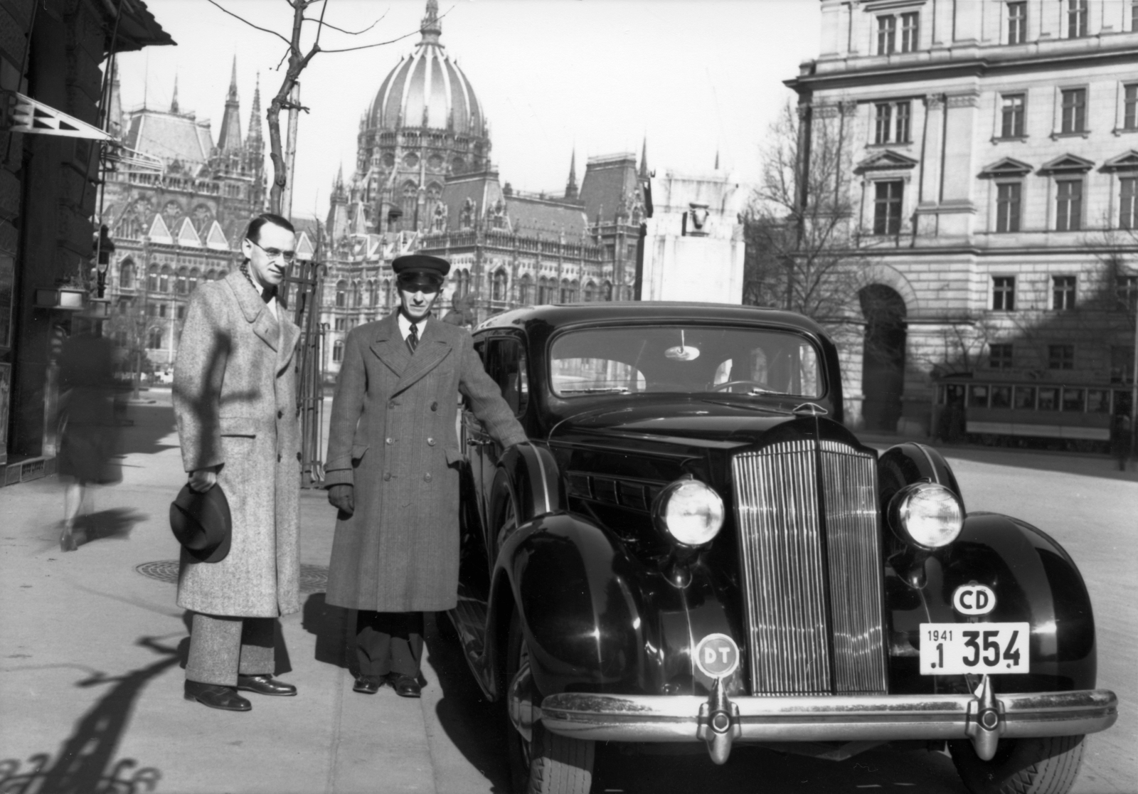 Magyarország, Budapest V., Vértanúk tere, balra Carl Lutz svájci diplomata. Háttérben a Nemzeti vértanúk emlékműve (Füredi Richárd, 1934.) és az Országház., 1943, Archiv für Zeitgeschichte ETH Zürich / Agnes Hirschi, Carl Lutz, amerikai gyártmány, sofőr, villamos, rendszám, Packard-márka, Budapest, sofőrsapka, diplomata jelzés, Fortepan #105822
