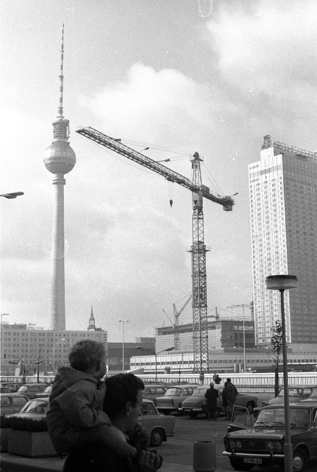 Germany, Berlin, Kelet-Berlin, Alexanderplatz az Otto Braun Strasse (Hans Beimler Strasse) felől nézve, háttérben a TV torony és a Hotel Stadt Berlin, előtérben a Haus des Reisens építkezése., 1969, Hunyady József, construction, crane, TV tower, GDR, East-Berlin, tower crane, tall house, modern architecture, department store, Hermann Henselmann-design, Roland Korn-design, Heinz Scharlipp-design, sitting on the shoulders, Josef Kaiser-design, Hans Erich Bogatzky-design, Johannes Briske-design, Roland Steiger-design, Günter Kunert-design, Fortepan #106265