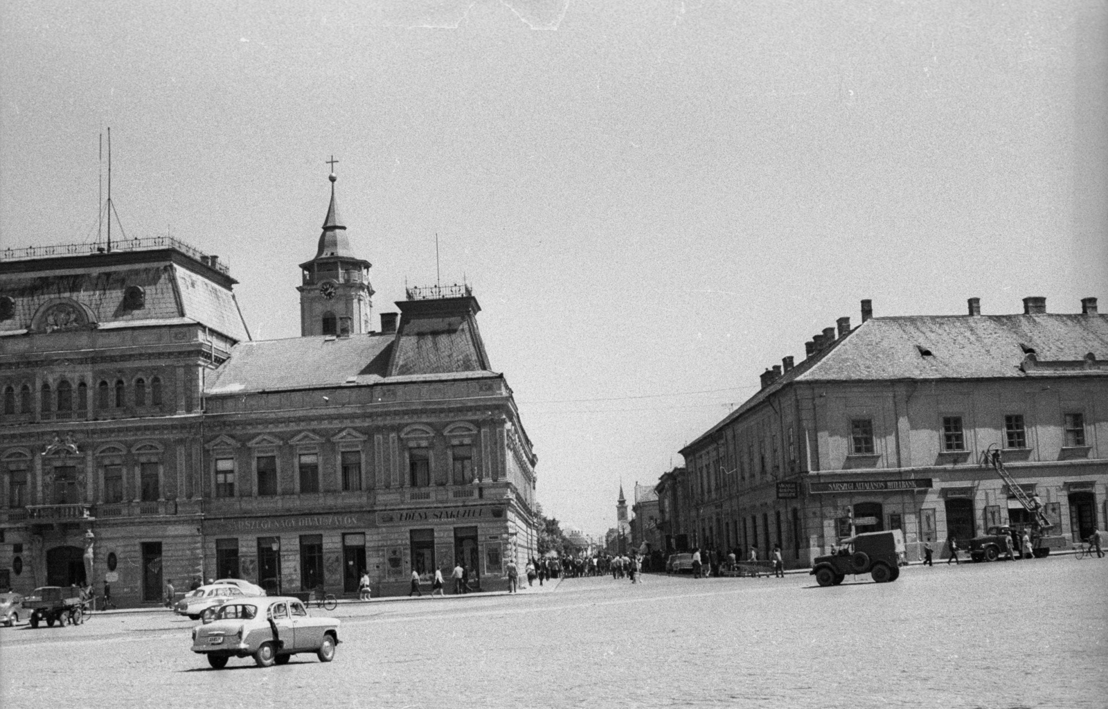 Magyarország, Baja, Szentháromság (Béke) tér a Deák Ferenc utca felé nézve. Balra a Városi Tanács épülete (később Városháza), mögötte a Páduai Szent Antal-templom tornya. A felvétel az Aranysárkány című film forgatásakor készült., 1966, Hunyady József, Fortepan #107283