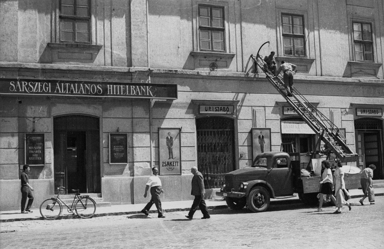 Hungary, Baja, Szentháromság (Béke) tér a Bajai Takarék Pénztár épülete. A felvétel az Aranysárkány című film forgatásakor készült., 1966, Hunyady József, filming, bicycle, pedestrian, commercial vehicle, ladder, Fortepan #107284