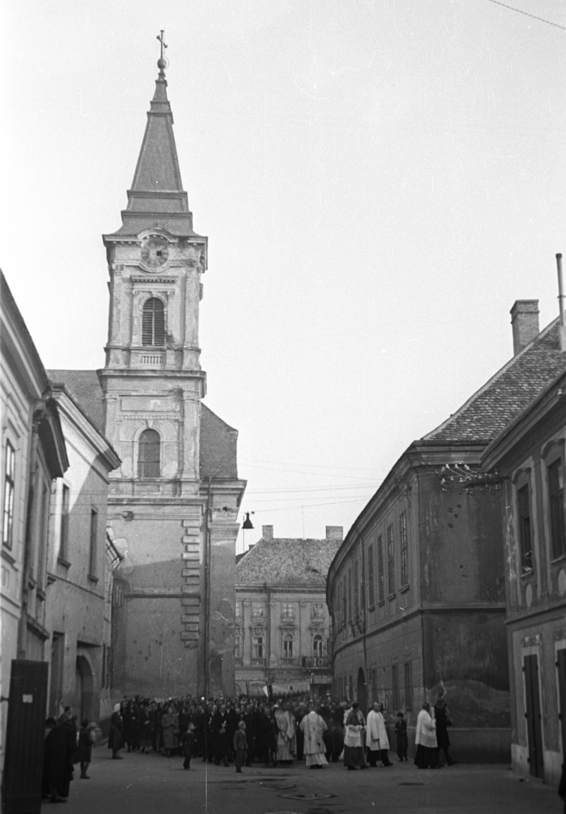 Magyarország, Székesfehérvár, Oskola (Zalka Máté) utca a Városház (Szabadság) tér felé nézve, szemben a Szent Imre-templom., 1956, Hámori Gyula, felvonulás, pap, kváderkő, golyónyom, tömeg, toronyóra, Fortepan #108386