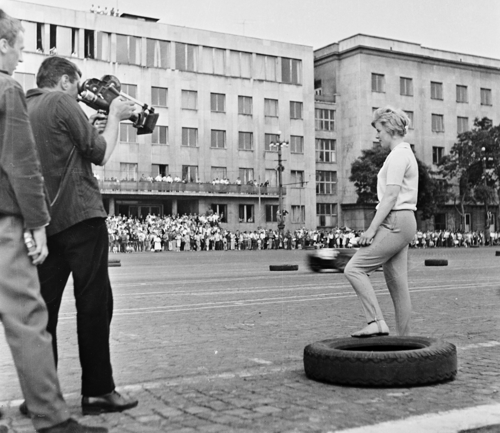 Hungary, Budapest VI.,Budapest XIV., Ötvenhatosok tere (Felvonulási tér), szemben a Dózsa György út 84. SZOT székház. A felvétel az Autóklub nemzetközi gyorsasági autóversenyén, az első Budapesti Grand Prix-n készült 1963. június 9-én., 1963, Bauer Sándor, street view, car race, movie camera, cobblestones, tire, Budapest, Fortepan #109469
