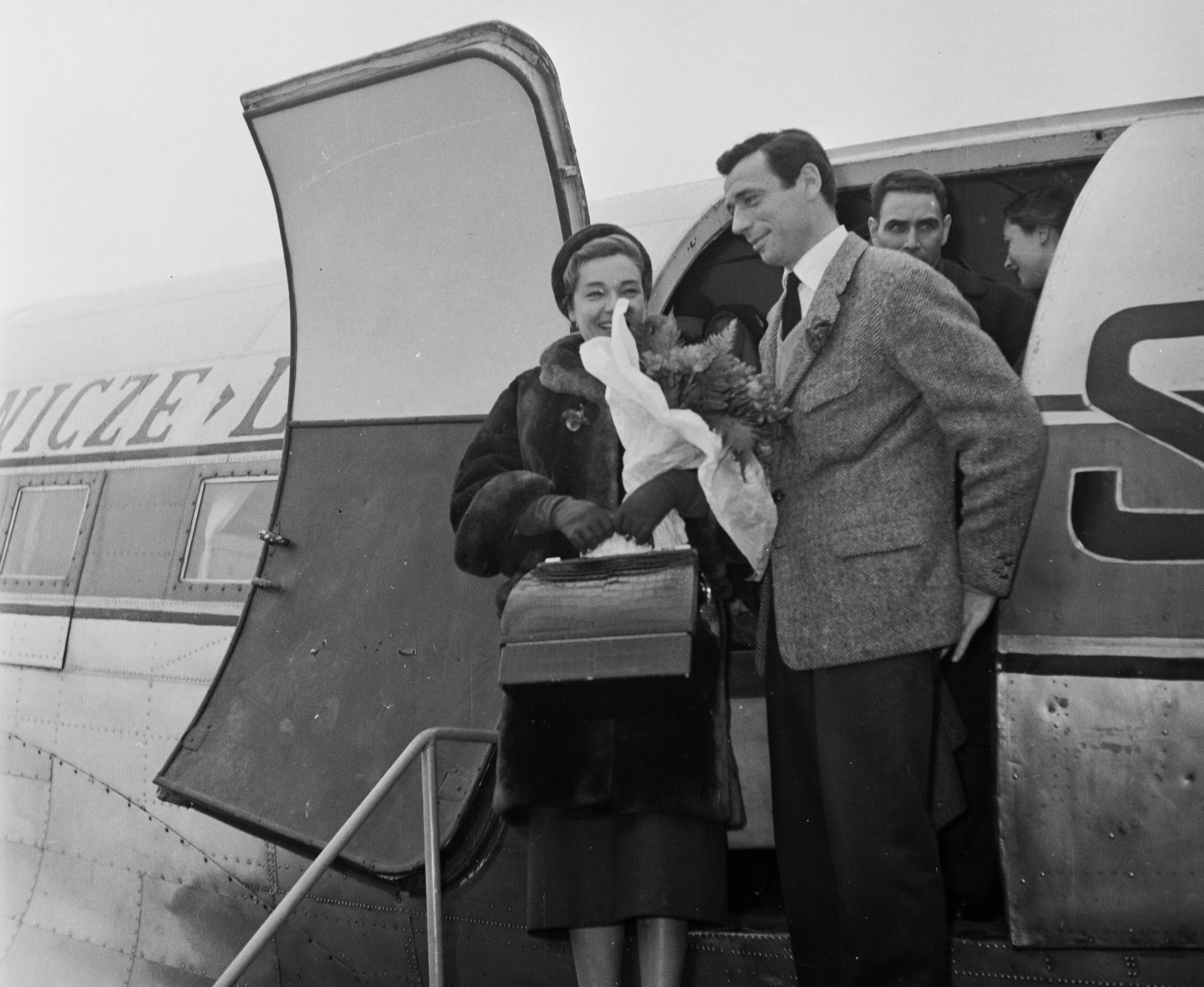 Magyarország, Ferihegyi (ma Liszt Ferenc) repülőtér, Budapest XVIII., Simone Signoret színművésznő és férje Yves Montand sanzonénekes és filmszínész. A háttérben a Polskie Linie Lotnicze LOT lengyel légitársaság Douglas DC-3 / C-47 típusú repülőgépe látható., 1957, Bauer Sándor, híres ember, repülőgép, emberpár, repülőtér, retikül, virágcsokor, színész, LOT (Polish Airlines), Douglas DC-3, Budapest, énekes, reptéri lépcső, Fortepan #110110