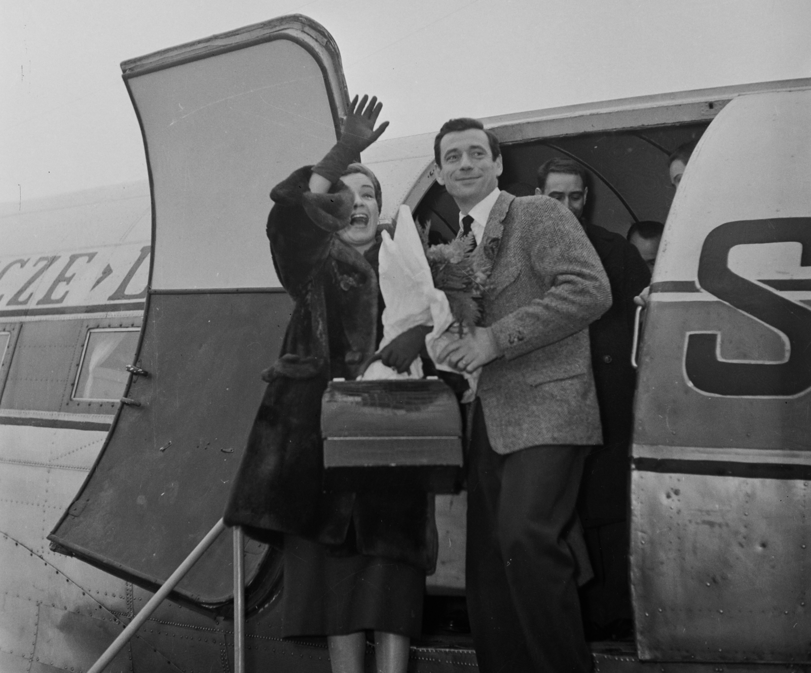 Hungary, Ferihegy (now - Ferenc Liszt) International Airport, Budapest XVIII., Simone Signoret színművésznő és férje Yves Montand sanzonénekes és filmszínész. A háttérben a Polskie Linie Lotnicze LOT lengyel légitársaság C-47 DC-3(C) típusú repülőgépe látható., 1957, Bauer Sándor, celebrity, smile, airplane, wave, man and woman, actor, Budapest, singer, aircraft steps, Fortepan #110111