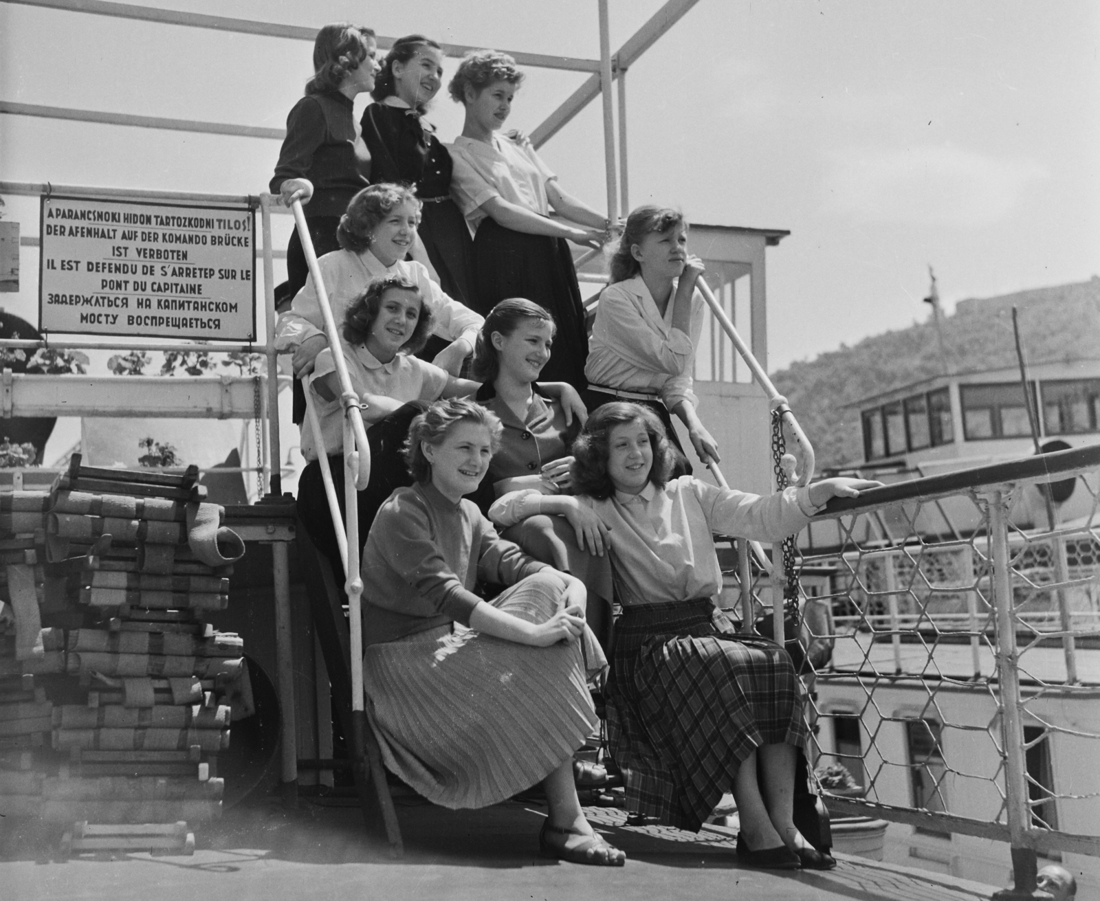 Hungary, Budapest V., Vigadó (Molotov) tér, hajóállomás. Jobbra fenn a Gellért-hegyen a Citadella és a Felszabadulási Emlékmű., 1956, Bauer Sándor, youth, railing, tableau, women, stairs, fun, boat trip, Budapest, multilingual sign, sitting on stairs, Fortepan #110136