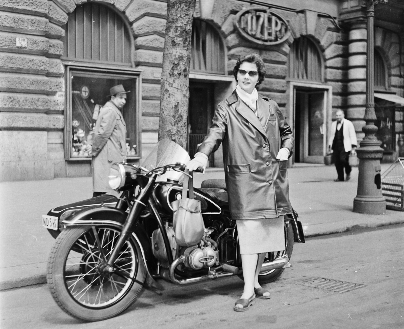 Hungary, Budapest VI., Andrássy út (Népköztársaság útja), BMW oldalkocsis motorkerékpár a 6-os számú ház előtt. Vitéz Eszter manöken., 1957, Bauer Sándor, fashion, motorcycle, BMW-brand, shades, bag, neon sign, Budapest, grocery store, emblem, girls'n'cars, neck scarf, motorcycle with sidecar, Közért Company, Fortepan #110344