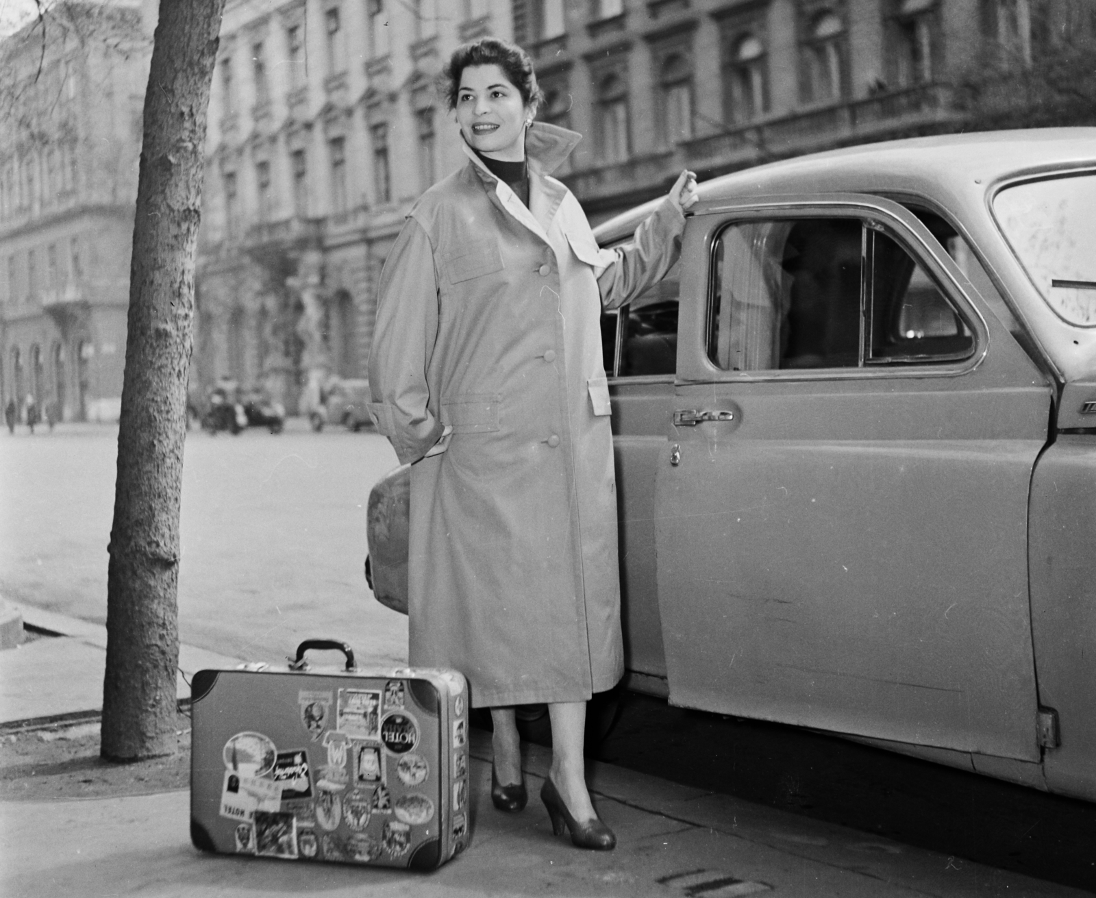 Magyarország, Budapest VI., Andrássy út (Népköztársaság útja), Pobjeda típusú személygépkocsi a 4-es szám előtt, szemben a 9-es és a 7-es számú ház látszik., 1957, Bauer Sándor, divat, cipő, bőrönd, automobil, GAZ M20 Pobeda, manöken, Budapest, bőröndcímke, lányok-járművek, Fortepan #110348