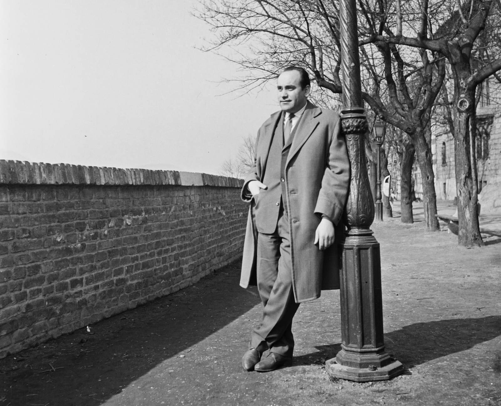 Magyarország, budai Vár, Budapest I., Tóth Árpád sétány, háttérben a 32. számú épület. Koppány György fotóriporter., 1963, Bauer Sándor, portré, férfi, póz, öltöny, téglakerítés, Budapest, zsebredugott kéz, felöltő, átvetett láb, Fortepan #110434