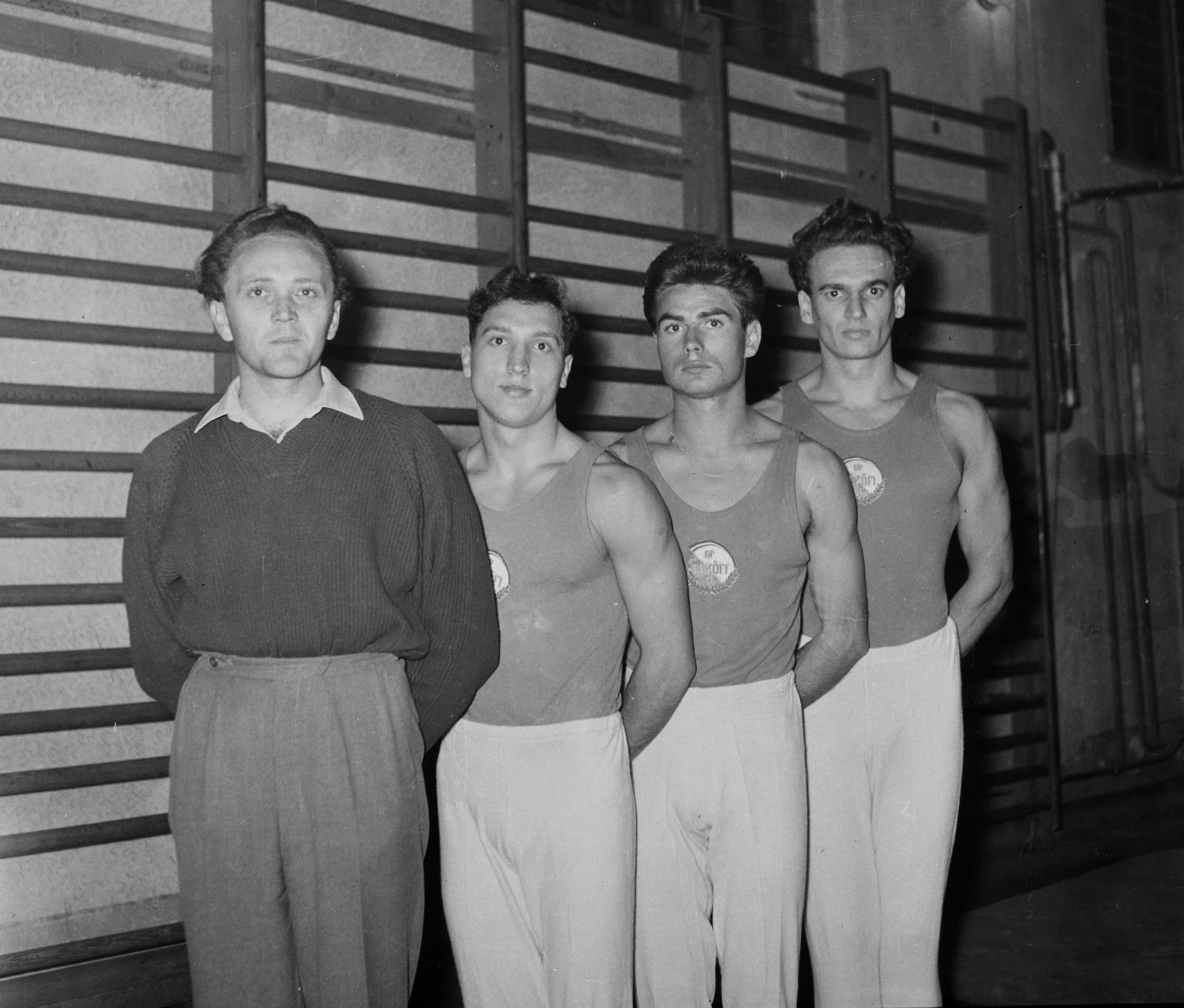 Hungary, a BP Petőfi SC sportolói., 1957, Bauer Sándor, tableau, men, wall-bars, athletic dress, hands behind the back, emblem, height chart, gymnast, Fortepan #111833