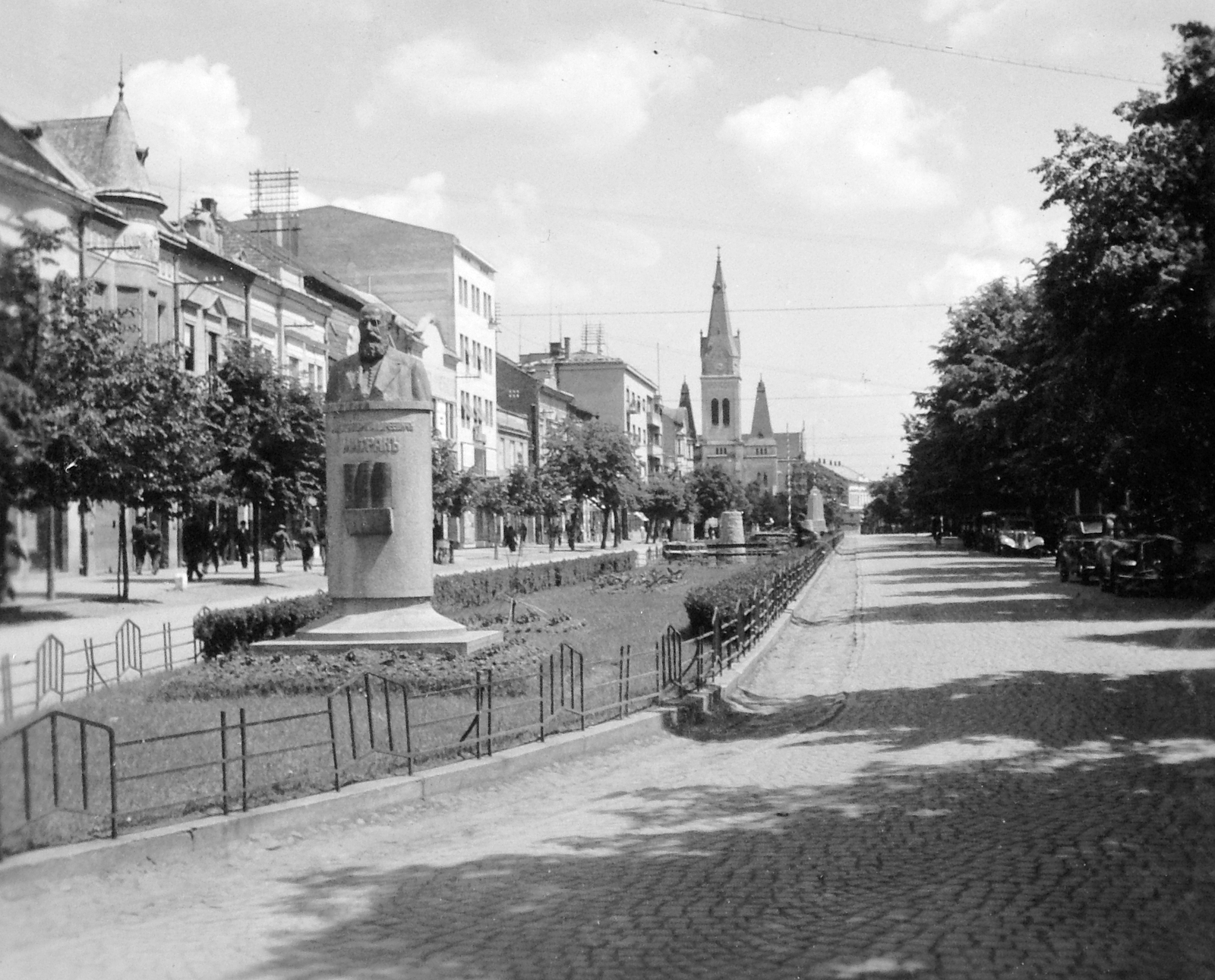 Ukraine,Zakarpattia Oblast, Mukachevo, Cirill és Metód tér (ekkor Horthy Miklós utca), a távolban a Tours-i Szent Márton-székesegyház., 1940, Gyöngyi, sculpture, aerial wire, cobblestones, bust, Fortepan #11458