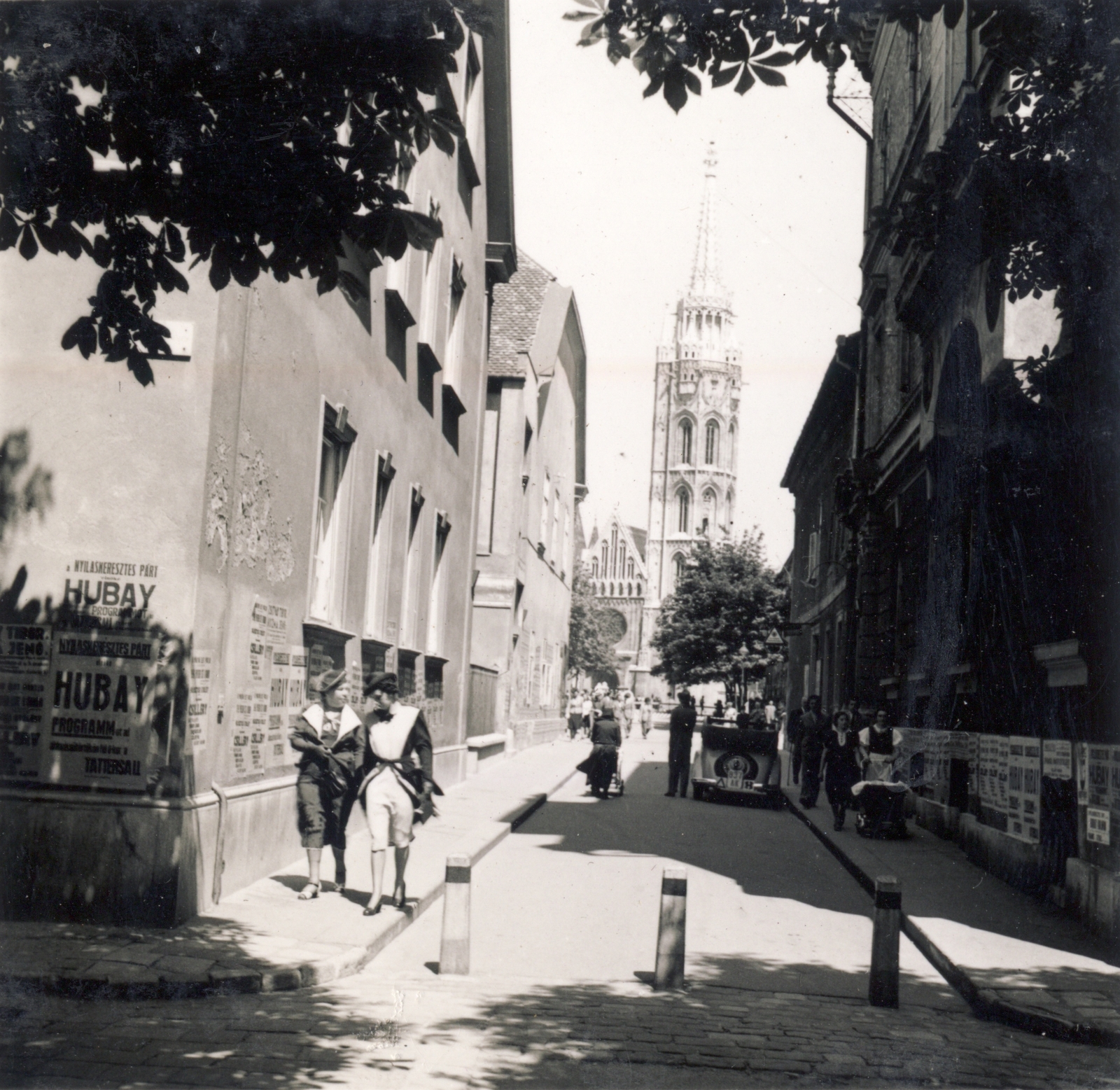 Magyarország, budai Vár, Budapest I., Szentháromság utca a Tóth Árpád sétányról (Gróf Bethlen István bástyasétány) nézve, szemben a Mátyás-templom., 1939, Buzinkay Géza, Budapest, utcakép, nők, plakát, Fortepan #114660