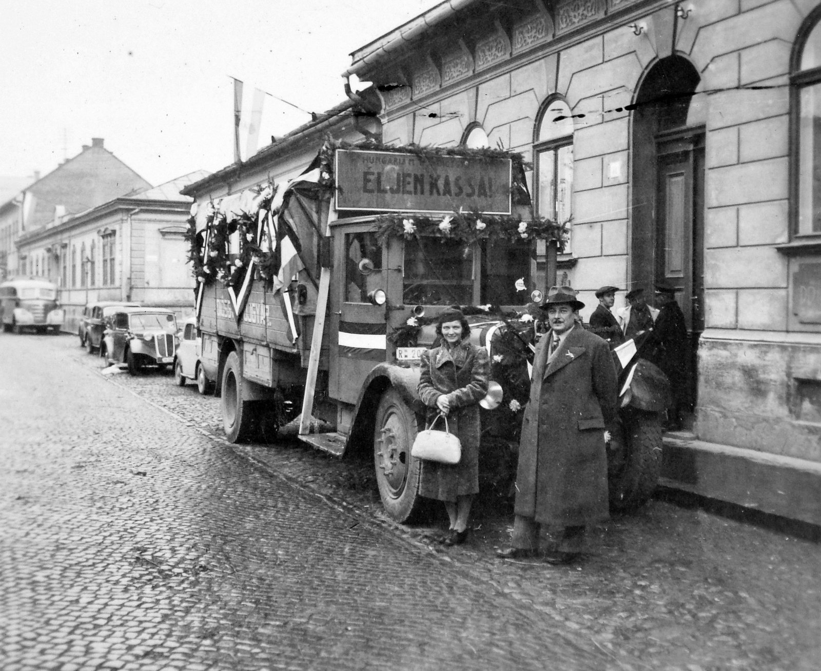 Szlovákia, Kassa, 1938, Gyöngyi, Csehszlovákia, területgyarapodás, autóbusz, zászló, virágdíszítés, kockakő, automobil, rendszám, hátratett kéz, pódiumautó, teherautó, Fortepan #11512