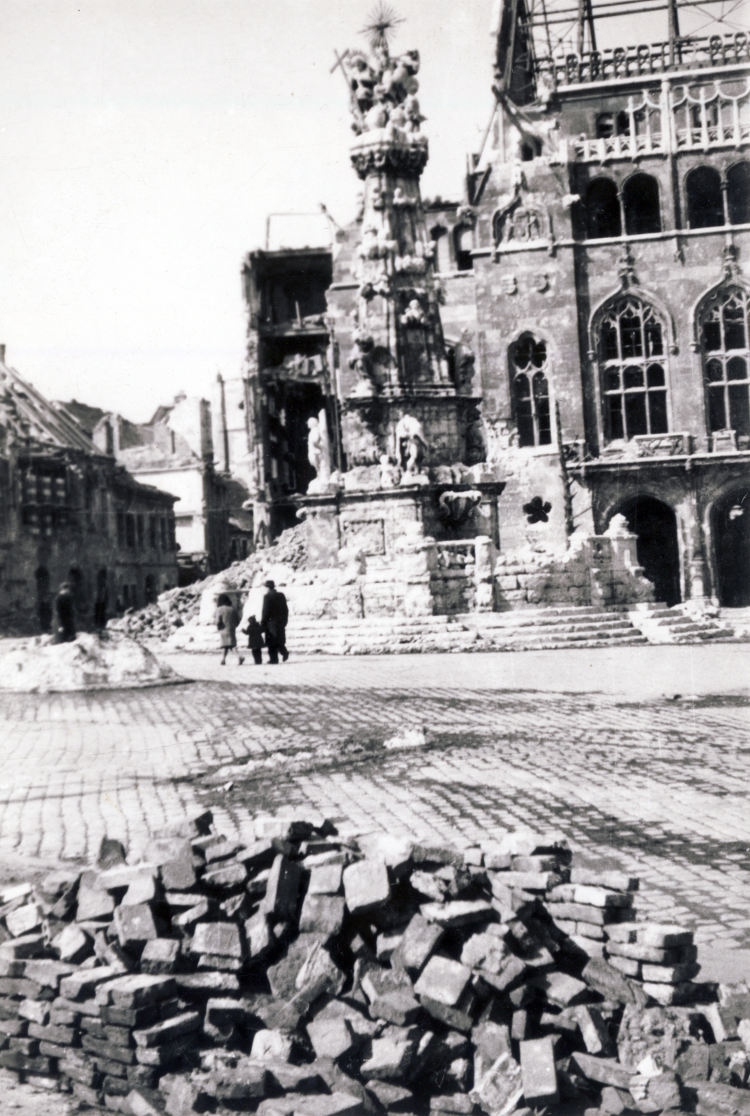 Magyarország, budai Vár, Budapest I., Szentháromság tér, Szentháromság-szobor, mögötte a Pénzügyminisztérium lerombolt épülete, balra az Országház utca., 1945, Széman György, kockakő, tégla, Budapest, Fortepan #115868