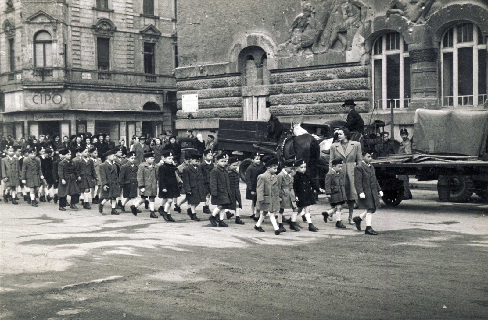 Hungary, Budapest VIII., Horváth Mihály (Mária Terézia) tér, balra a Német (Bacsó Béla) utca torkolata. Jobbra a József Telefonközpont épülete., 1945, Fortepan/Album009, Budapest, Horse-drawn carriage, march, kid, gaping, uniform, "Bocskai" side cap, school, Fortepan #116497
