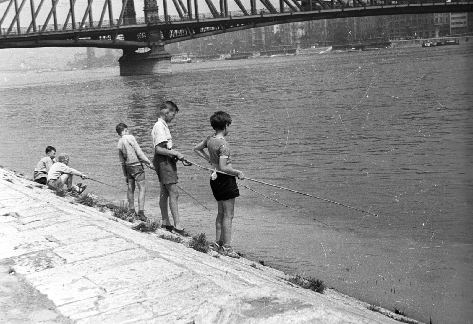 Magyarország, Budapest V.,Budapest XI., budai alsó rakpart a Szent Gellért tér alatt, szemben a Szabadság híd és a Belgrád rakpart házsora, távolban a Széchenyi Lánchíd., 1957, FSZEK Budapest Gyűjtemény / Sándor György, Sándor György, horgászat, gyerekek, Budapest, Duna-part, Fortepan #116982