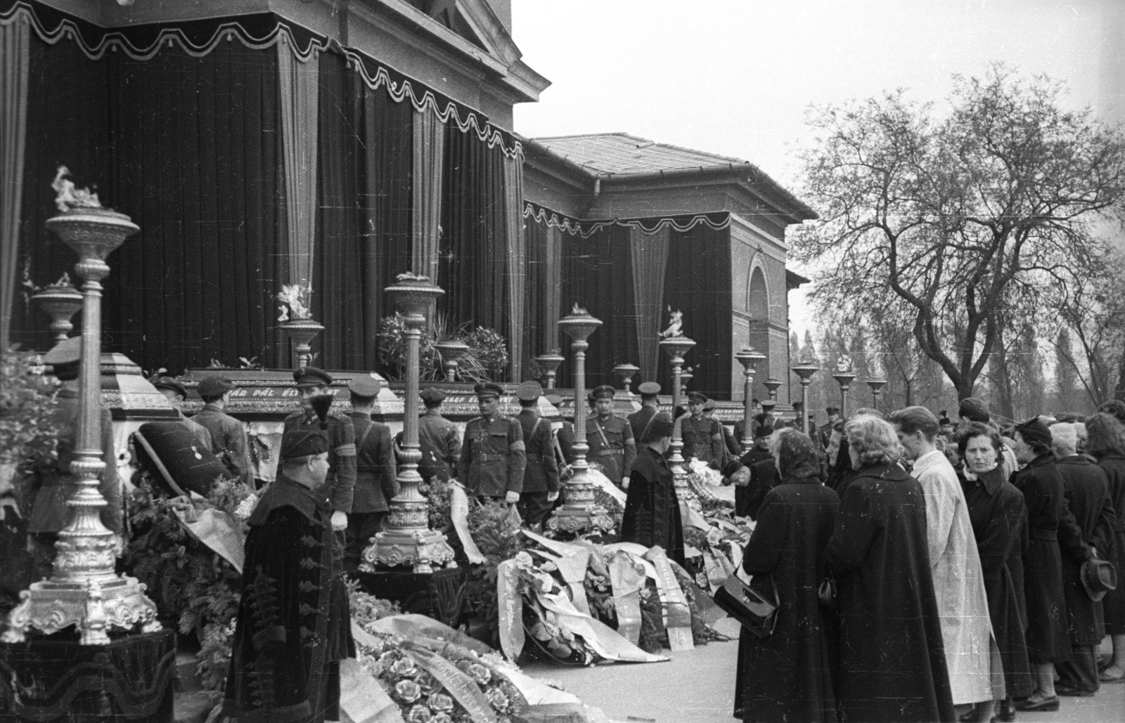 Magyarország, Budapest VIII., Fiumei úti Nemzeti Sírkert (Kerepesi temető) 1957. április 19-én. Az 1956. októberében a rádiónál és a Kertész utcánál elesett tisztek koporsója a ravatalozó előtt., 1957, FSZEK Budapest Gyűjtemény / Sándor György, Sándor György, Budapest, drapéria, gyászhuszár, koszorú, Fortepan #117091