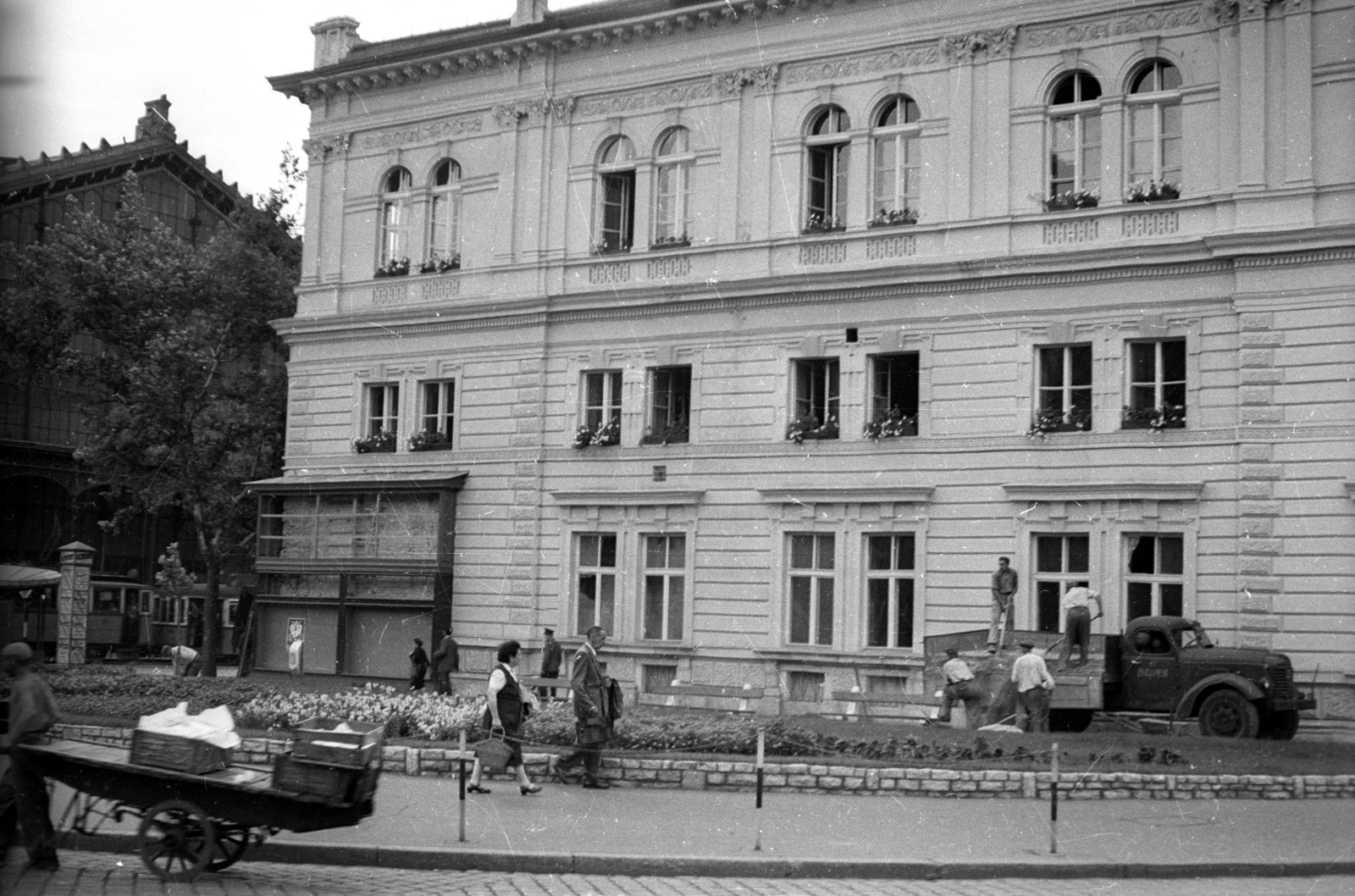 Magyarország, Budapest VI., Teréz (Lenin) körút - Nyugati (Marx) tér sarok, balra a Nyugati pályaudvar, jobbra az egykori indóházból kialakított MÁV BVKH / Bevételellenőrzési, Visszatérítési és Kártérítési Hivatal., 1958, FSZEK Budapest Gyűjtemény / Sándor György, Sándor György, Budapest, kézikocsi, teherautó, Fortepan #117138