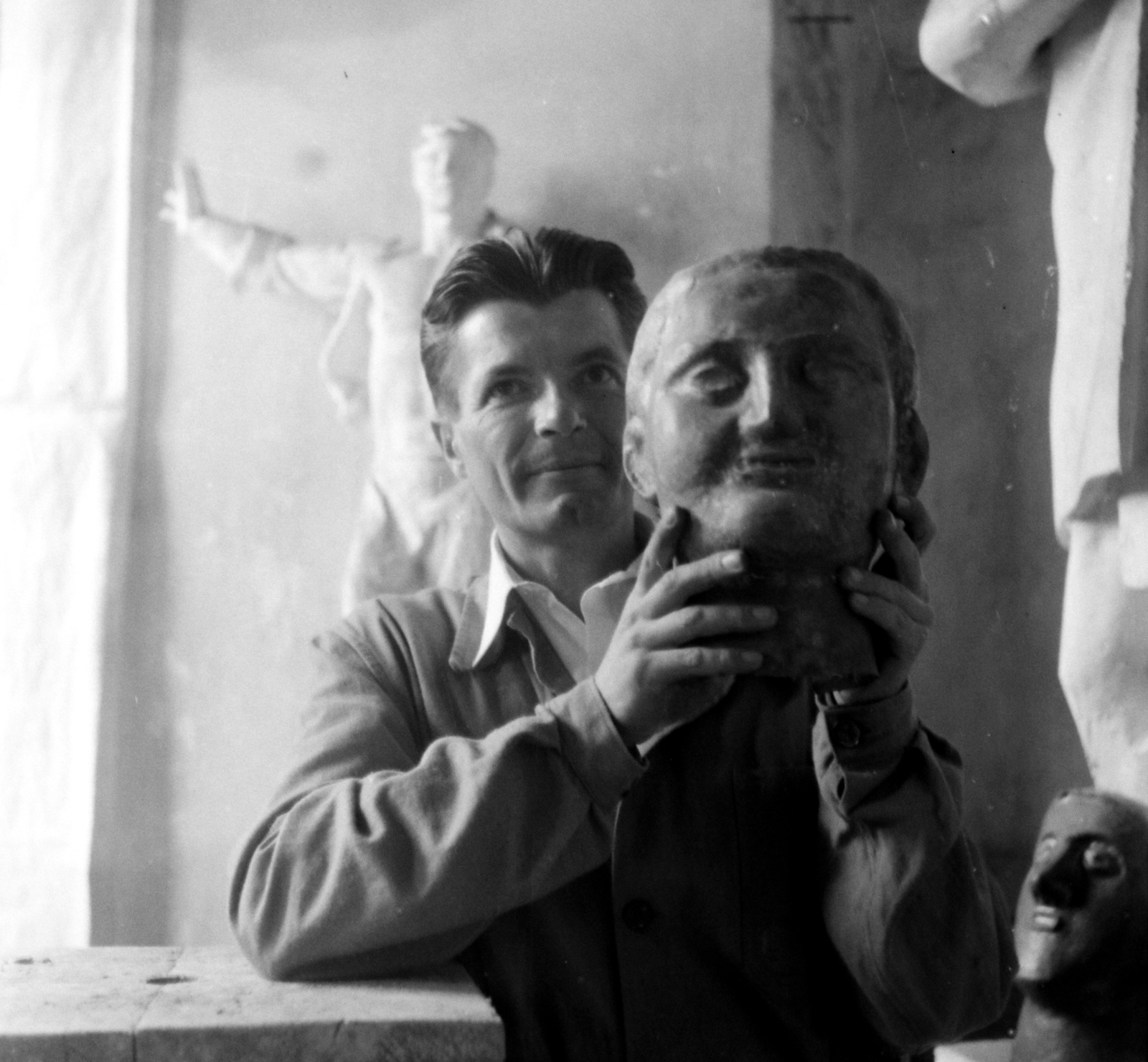 Magyarország, Budapest I., Várkert Bazár, Megyeri Barna szobrászművész a műtermében. Háttérben a Prométheusz című épületdísz gipszmintája., 1956, Aradi Péter, Szenczi Mária, műterem, híres ember, kézben tartani, Budapest, Fortepan #117402