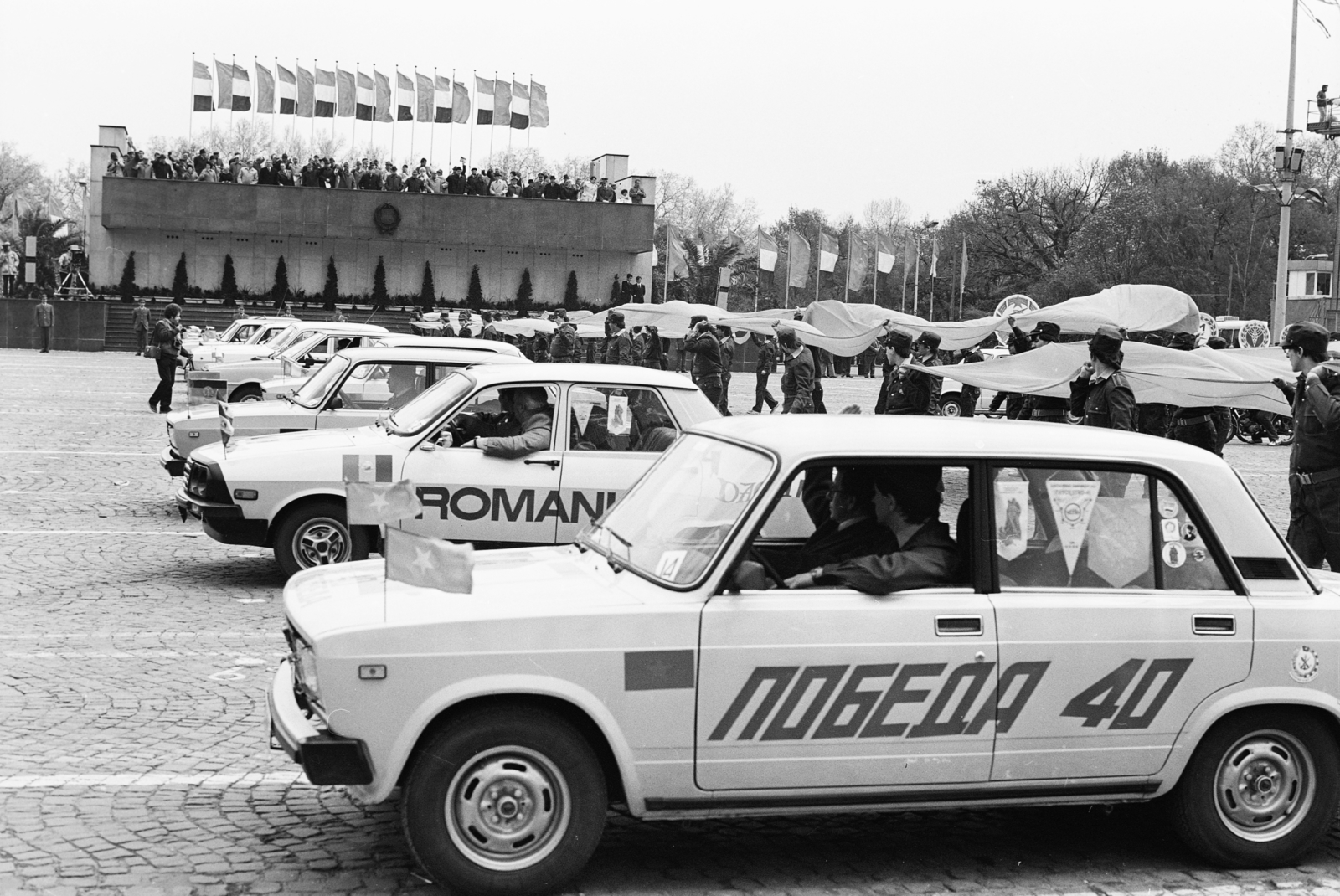 Magyarország, Budapest XIV., Ötvenhatosok tere (Felvonulási tér), május 1-i felvonulás, szemben a dísztribün., 1985, MHSZ, ünnepség, Dacia-márka, címer, Budapest, cirill írás, Fortepan #118407