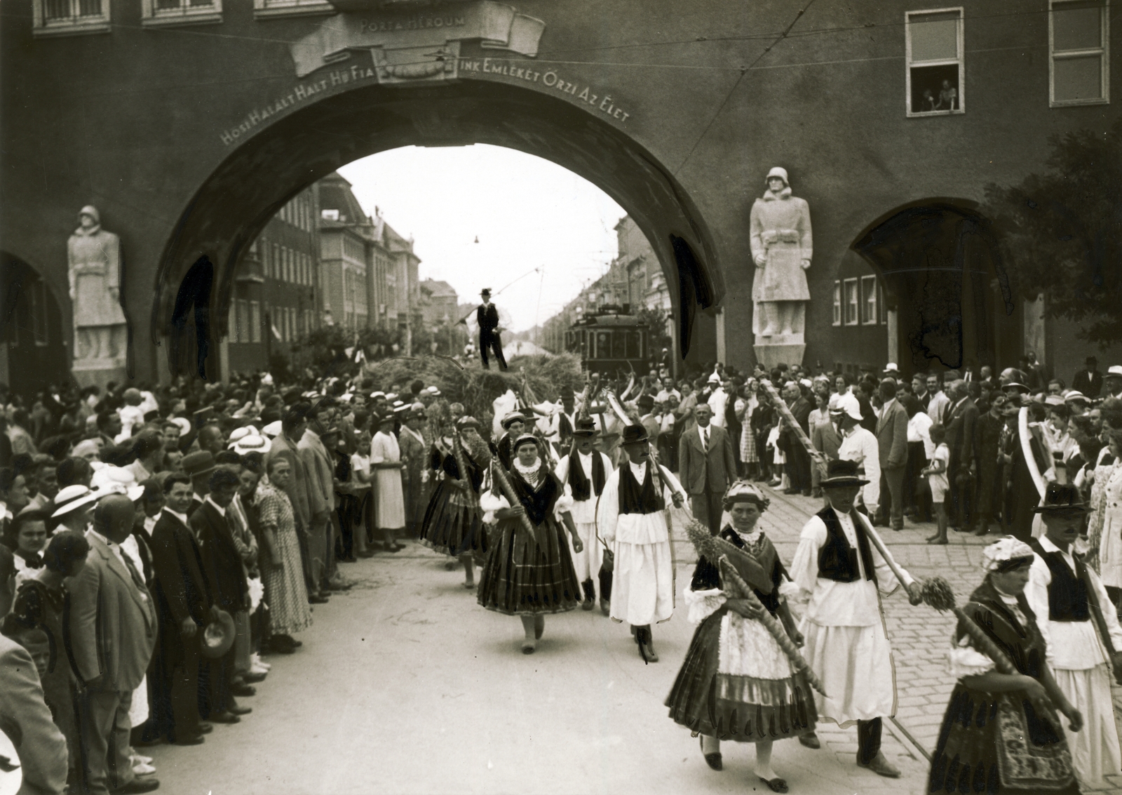 Magyarország, Szeged, Aradi vértanúk tere (Gizella tér), szemben a Hősök kapuja. Aratók felvonulása., 1937, Uj Nemzedék napilap, kapu, szobor, emlékmű, ünnepség, villamos, felvonulás, népviselet, papucs, neoklasszicizmus, Pogány Móric-terv, Gyöngyösbokréta Mozgalom, Fortepan #118789