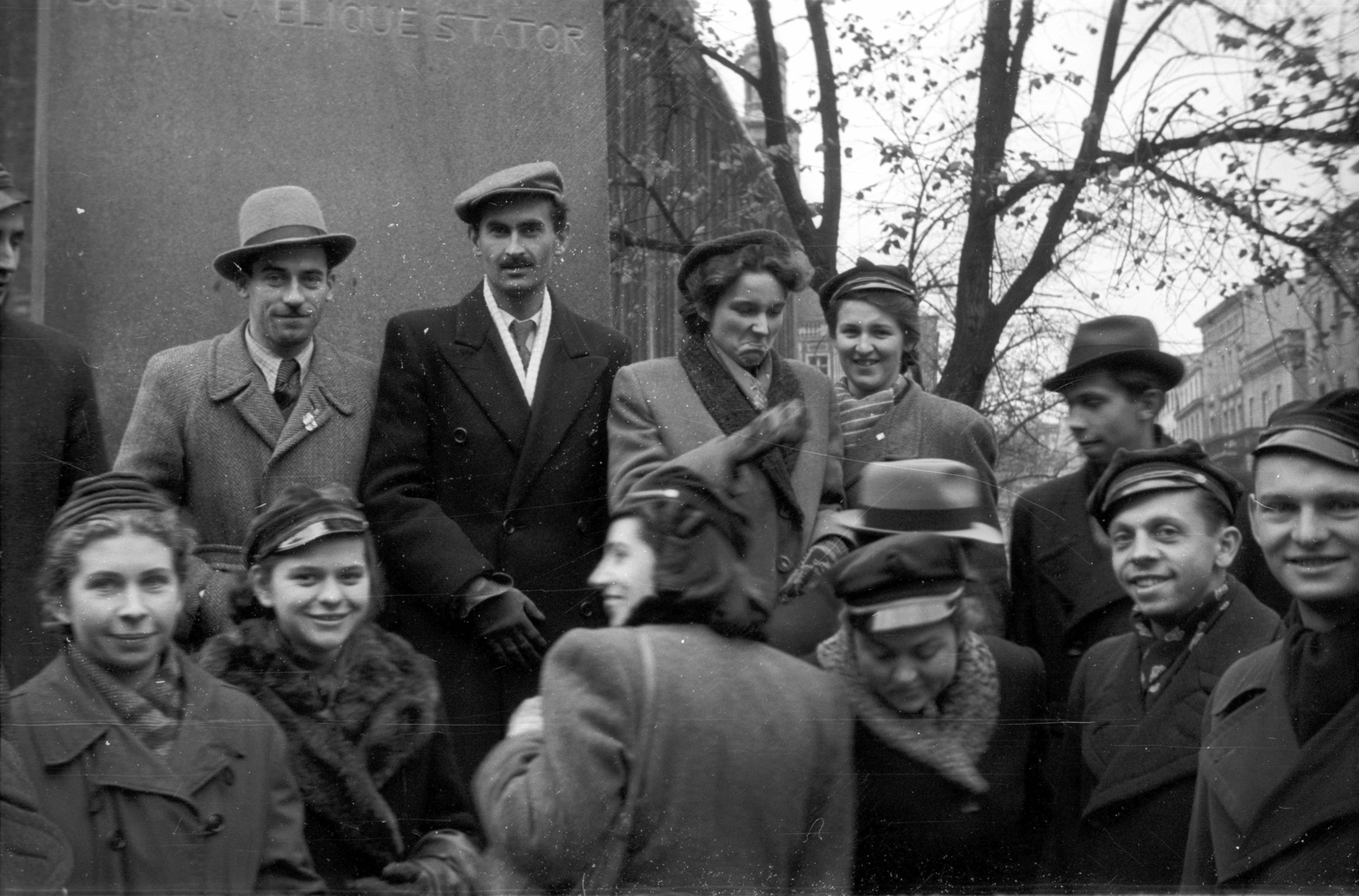 Lengyelország, Toruń, Rynek Staromiejski, a felvétel a Kopernikusz emlékműnél készült, háttérben a Régi Városháza., 1946, Bogdan Celichowski, sapka, úriember, hölgy, csoportkép, mosoly, kabát, kalap, Fortepan #119238