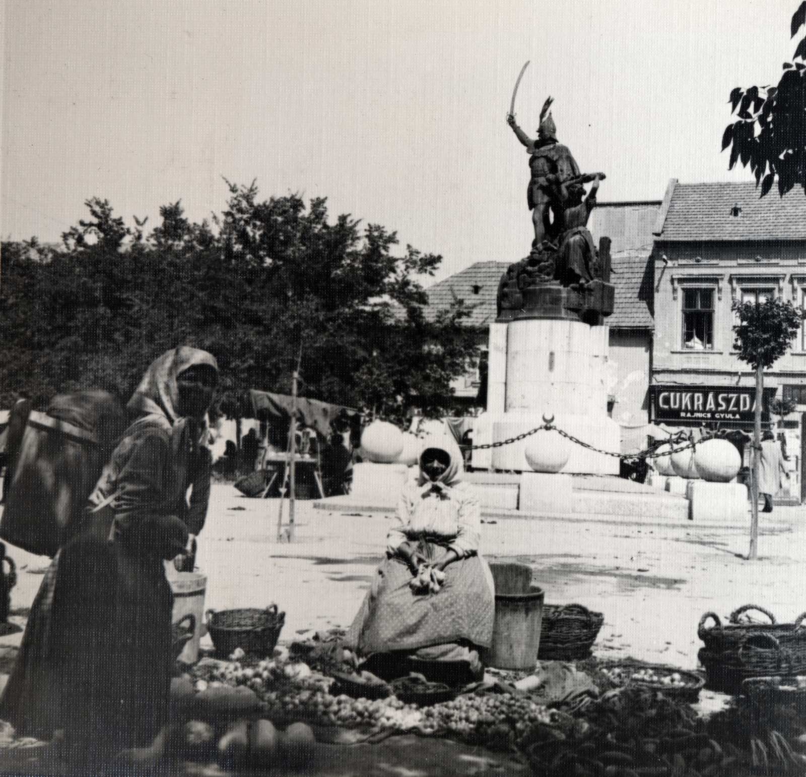 Magyarország, Eger, piac a Dobó István (Kossuth) téren, háttérben Dobó István szobra (Stróbl Alajos, 1907.)., 1932, Kurutz Márton, cégtábla, piac, cukrászda, gyümölcs, kosár, kofa, puttony, gyümölcsárus, Dobó István-ábrázolás, Fortepan #11961