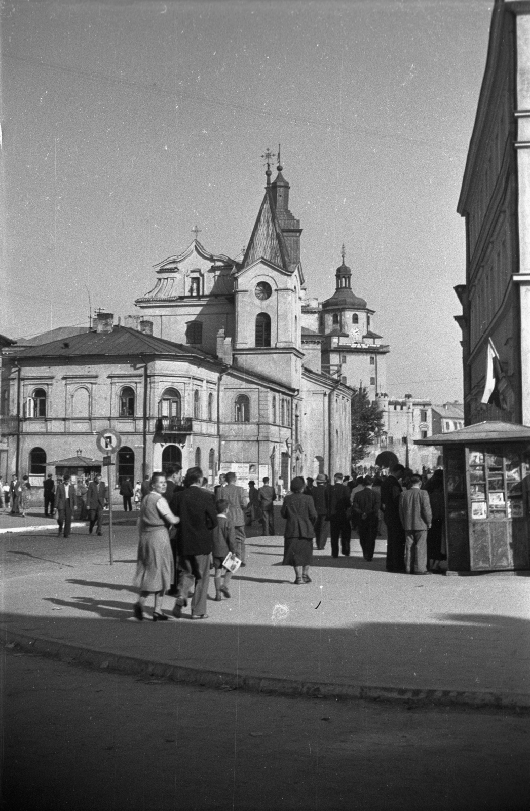 Lengyelország, Lublin, ulica Krakowskie Przedmieście - ulica Walerego Wróblewskiego sarok. Szemben a Szentlélek-templom (Kościół Świętego Ducha), háttérben a Városháza tornya és a Krakkói Kapu (Brama Krakowska)., 1948, Bogdan Celichowski, templom, utcakép, járókelő, újságárus, Fortepan #119776