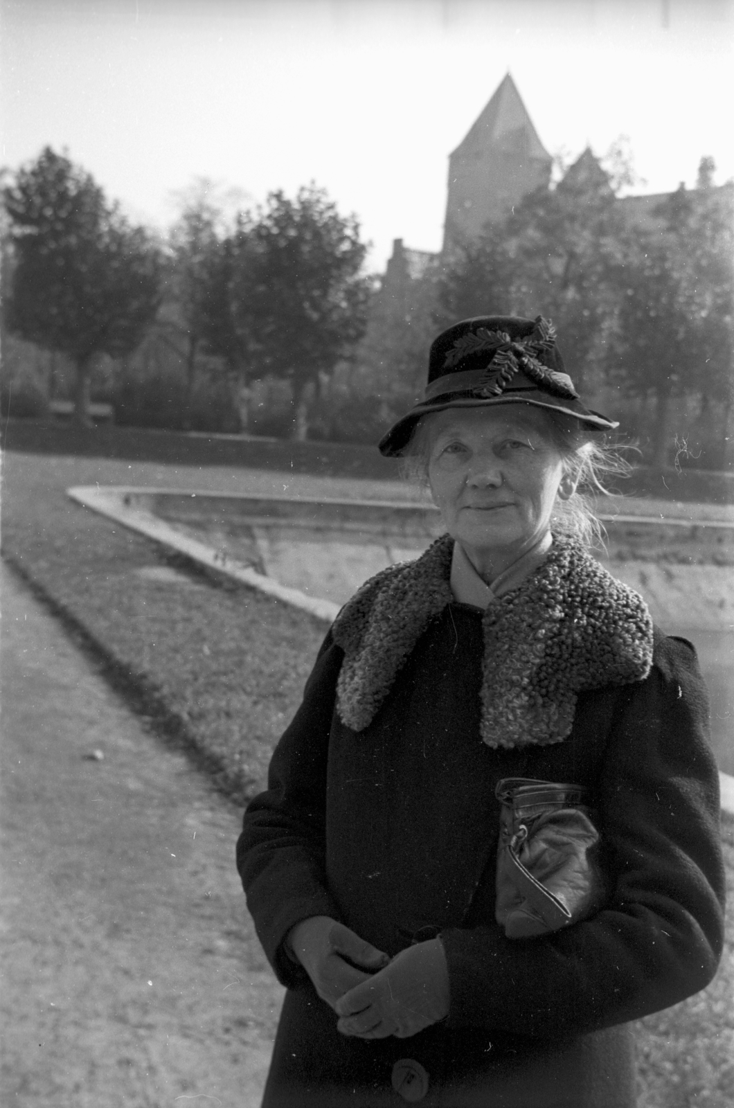 Lengyelország, Poznań, Mickiewicz park a Nagyszínház (Teatr Wielki im. Stanisława Moniuszki) előtt, háttérben az Imperial Kastély (később kulturális központ)., 1948, Bogdan Celichowski, kalap, kabát, hölgy, Fortepan #120028