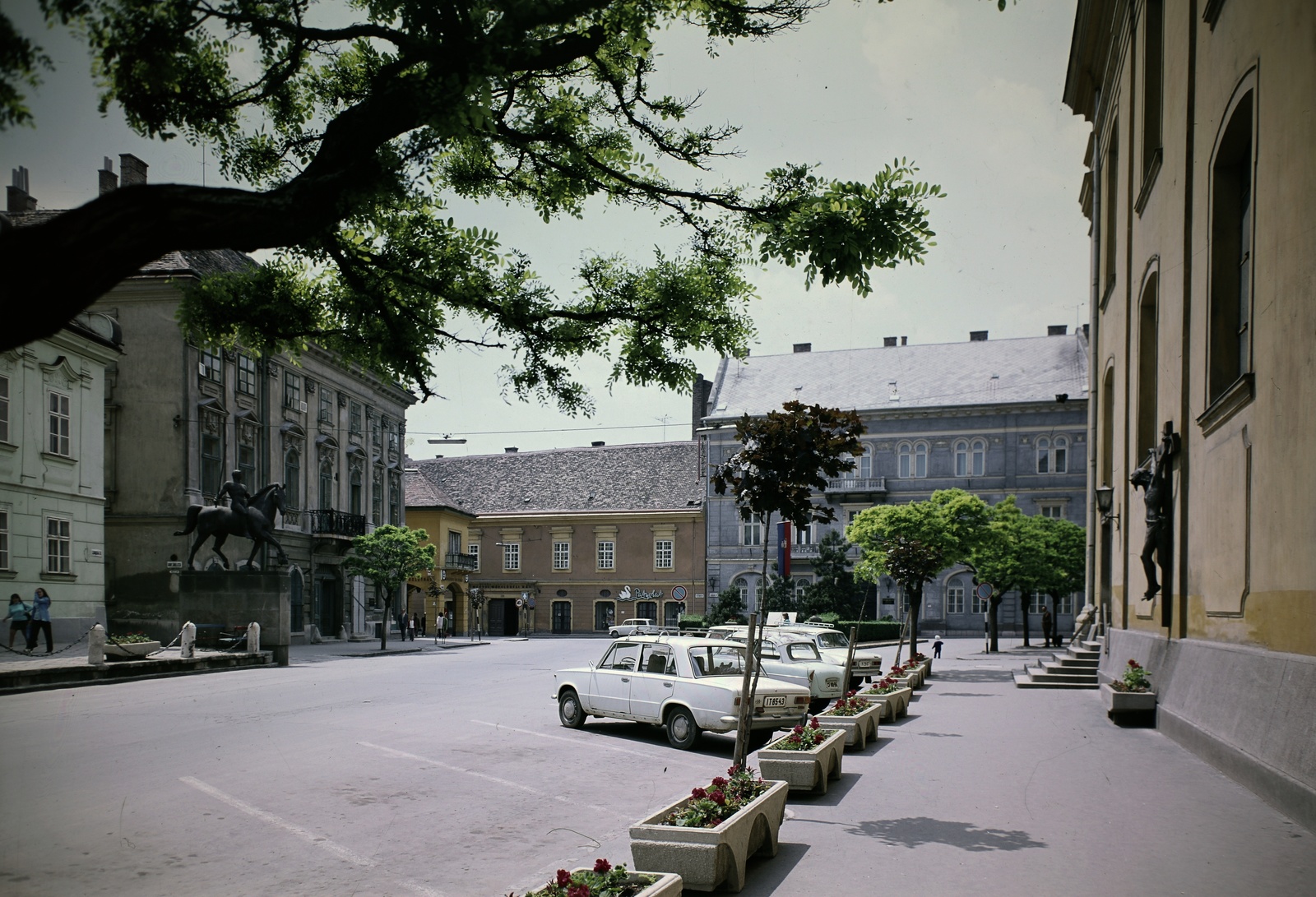 Hungary, Székesfehérvár, Városház (Szabadság) tér, a kép bal szélén a Városháza épületének sarka látszik, előtte a Tízes huszárok szobra. Jobbra a Szent Imre-templom., 1973, Inkey Tibor, colorful, car park, Fortepan #120940