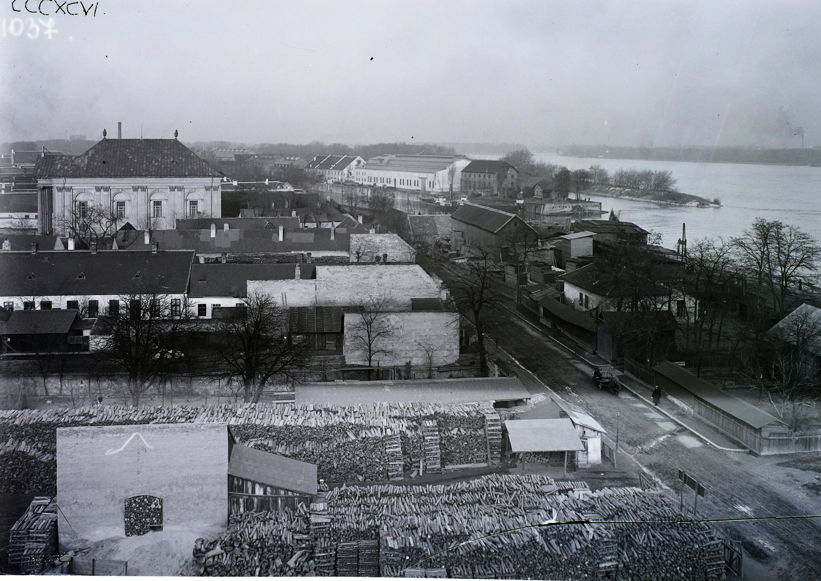 Magyarország, Óbuda, Budapest III., fatelep az Árpád fejedelem útja (ekkor ez az útszakasz Rupp Imre utca) mellett. Távolabb balra az Óbudai zsinagóga és jobbra az Óbudai Hajógyár. Leltári jelzet: MMKM TFGY 2017.2.41., 1925, Magyar Műszaki és Közlekedési Múzeum / Történeti Fényképek Gyűjteménye / Óbudai Hajógyár gyűjteménye, Budapest, Fortepan #122003