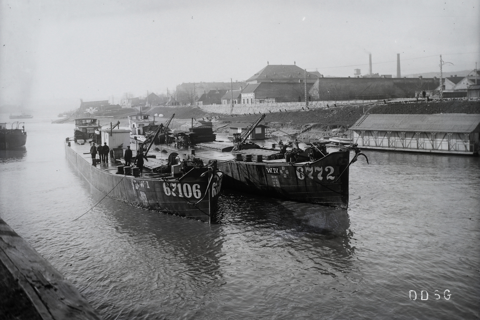 Hungary, Óbuda, Budapest III., Óbudai Hajógyár, Duna-ág a Hajógyári-sziget mellett, DDSG uszálybárkák, jobbra úszó csónakház. Háttérben a szentendrei HÉV vonala és a házak között az Óbudai zsinagóga tetőzete emelkedik ki. Leltári jelzet: MMKM TFGY 2017.2.312., 1930, Magyar Műszaki és Közlekedési Múzeum / Történeti Fényképek Gyűjteménye / Óbudai Hajógyár gyűjteménye, barge, Budapest, Fortepan #122153