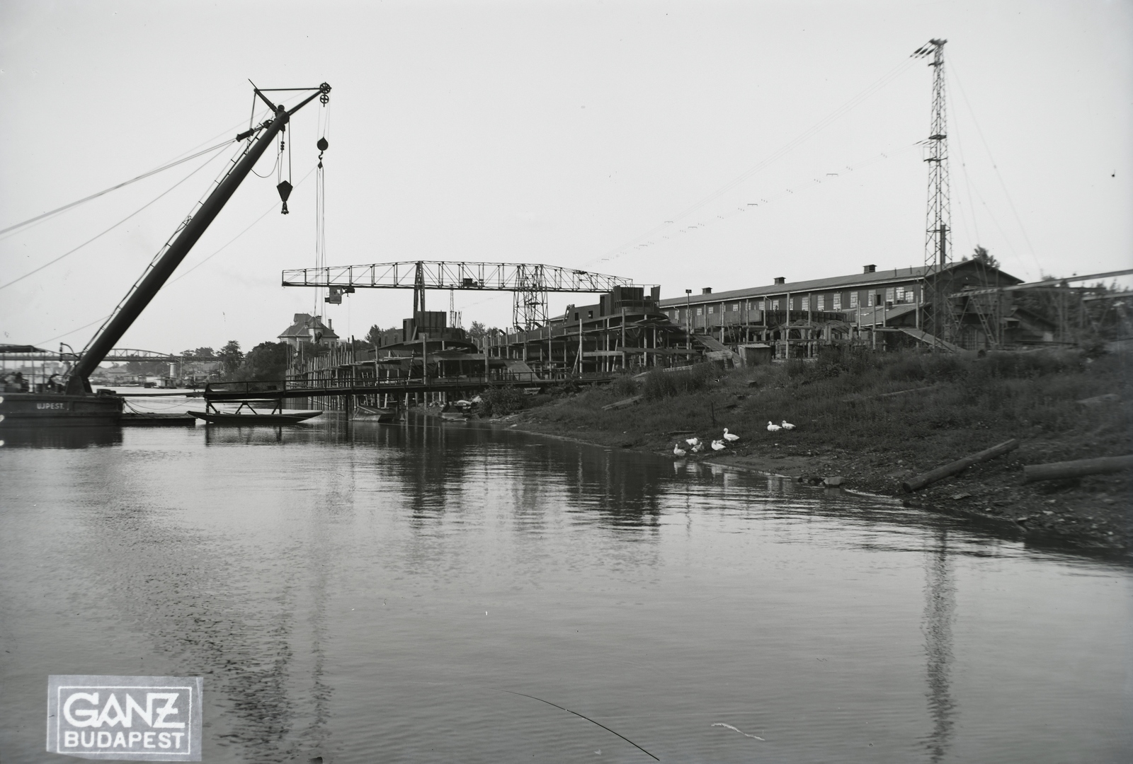 Hungary, Budapest XIII., Újpesti-öböl, Ganz és Tsa. Villamossági-, Gép-, Waggon- és Hajógyár Rt. Shell tankuszály építése, a part mellett az Újpest (1906) úszódaru, háttérben az Újpesti vasúti híd. Leltári jelzet: MMKM TFGY 2017.1.84., 1937, Magyar Műszaki és Közlekedési Múzeum / Történeti Fényképek Gyűjteménye / Ganz gyűjtemény, barge, dredge, Budapest, gantry crane, Fortepan #122535