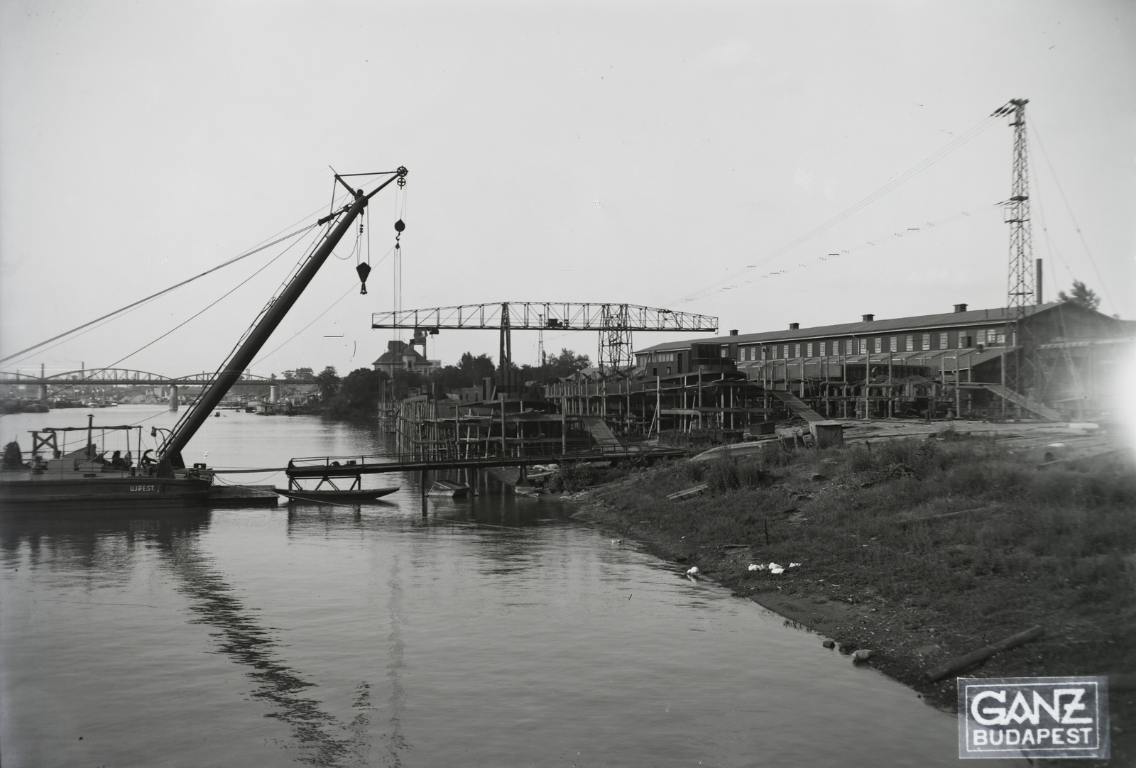 Hungary, Budapest XIII., Újpesti-öböl, Ganz és Tsa. Villamossági-, Gép-, Waggon- és Hajógyár Rt. Shell tankuszály építése, a part mellett az Újpest (1906) úszódaru, háttérben az Újpesti vasúti híd. Leltári jelzet: MMKM TFGY 2017.1.85., 1937, Magyar Műszaki és Közlekedési Múzeum / Történeti Fényképek Gyűjteménye / Ganz gyűjtemény, barge, dredge, Budapest, gantry crane, Fortepan #122536