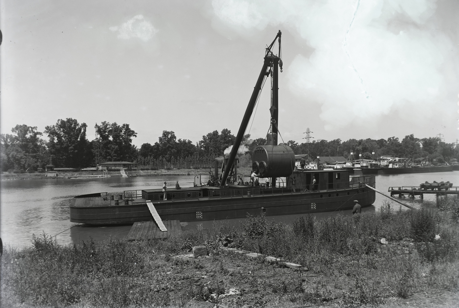 Magyarország, Budapest XIII., Újpesti-öböl, Ganz és Tsa. Villamossági-, Gép-, Waggon- és Hajógyár Rt. MFTR Vásárhelyi Pál (1936) tiszai csavaros vontató gőzhajó; kazán beemelése. Háttérben a Népsziget. Leltári jelzet: MMKM TFGY 2017.1.94., 1936, Magyar Műszaki és Közlekedési Múzeum / Történeti Fényképek Gyűjteménye / Ganz gyűjtemény, úszódaru, Budapest, Fortepan #122539