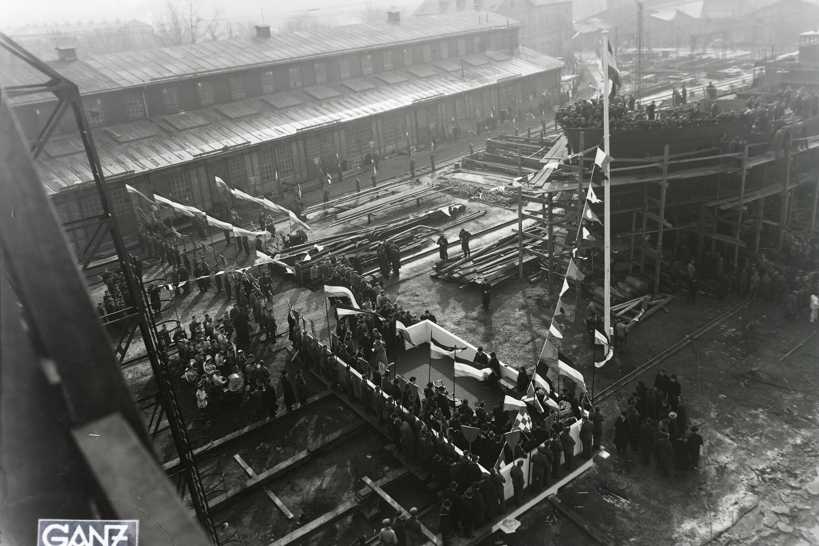 Hungary, Budapest XIII., Újpesti-öböl, Ganz és Tsa. Villamossági-, Gép-, Waggon- és Hajógyár Rt. A DTRT Ungvár (1941) duna-tengeri áruszállító csavaros motorhajó vízrebocsátási ünnepsége, előtérben a dísztribün. Leltári jelzet: MMKM TFGY 2017.1.480., 1941, Magyar Műszaki és Közlekedési Múzeum / Történeti Fényképek Gyűjteménye / Ganz gyűjtemény, Budapest, Fortepan #122738