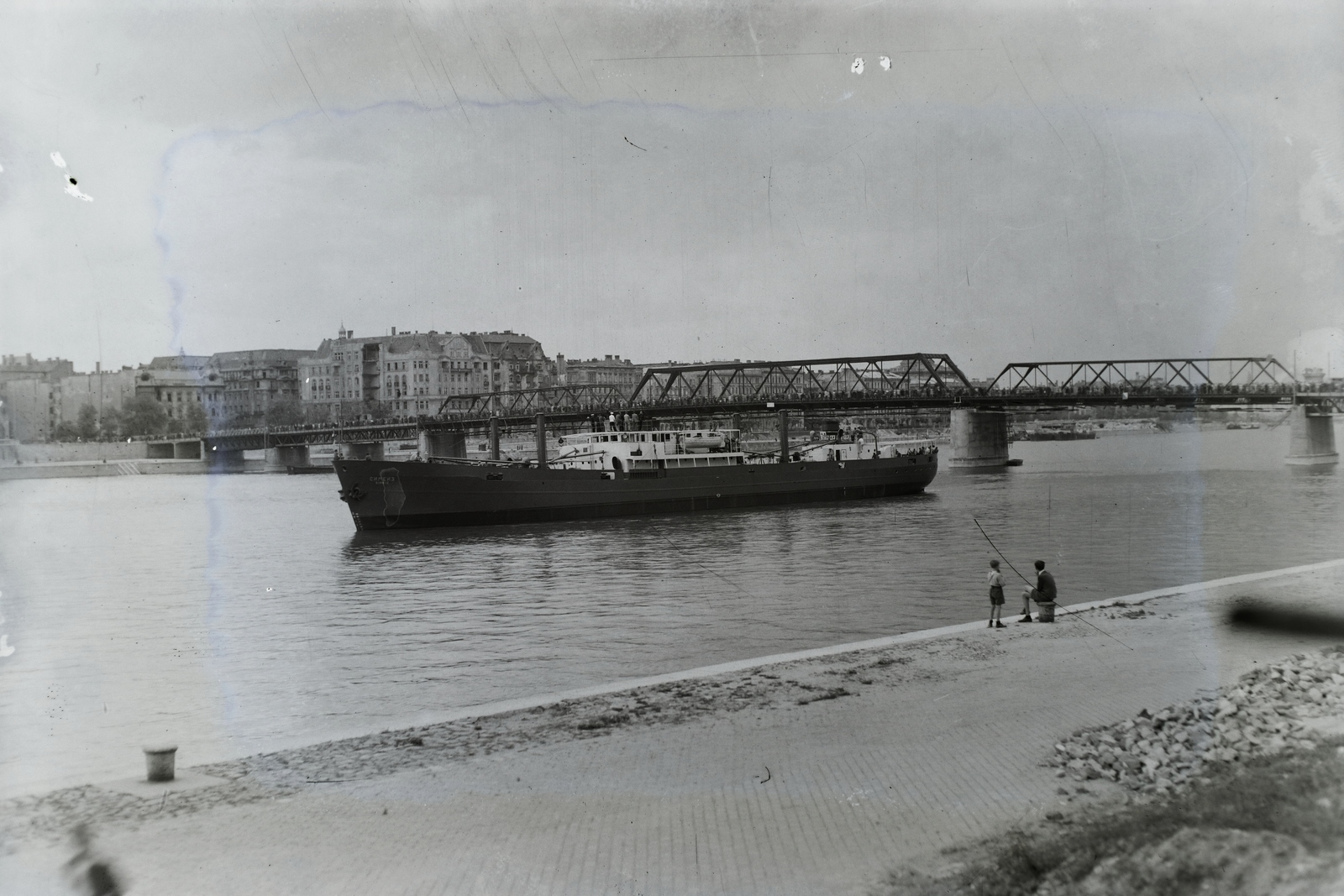 Hungary, Budapest V.,Budapest II., a jóvátételre gyártott Szimeiz (1946) Duna-tengerjáró motorhajó a Dunán a Kossuth hídnál, a budai alsó rakpartról nézve. Leltári jelzet: MMKM TFGY 2017.1.1061., 1946, Magyar Műszaki és Közlekedési Múzeum / Történeti Fényképek Gyűjteménye / Ganz gyűjtemény, Budapest, sitting, man, kid, Fortepan #122950