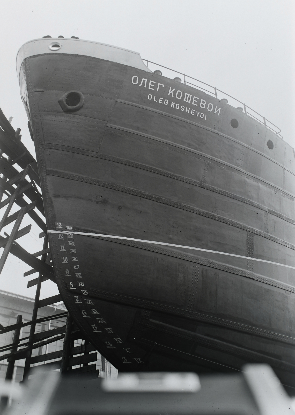Hungary, Budapest XIII., Újpesti-öböl, a Ganz Hajógyár sólyája, az Oleg Kosevoj (1950) 1100 tonnás tengeri áruszállító csavaros motorhajó /ép. sz. 1545/ vízrebocsátás előtt. Leltári jelzet: MMKM TFGY 2017.1.1420., 1950, Magyar Műszaki és Közlekedési Múzeum / Történeti Fényképek Gyűjteménye / Ganz gyűjtemény, Budapest, Cyrillic alphabet, bilingual sign, 1100 DWT-ship, Roman numerals, Fortepan #123076