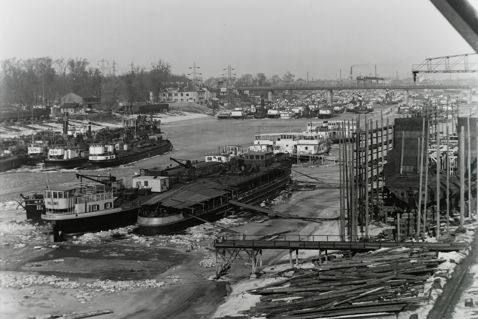 Hungary, Budapest XIII., Újpesti-öböl, Ganz és Tsa. Villamossági-, Gép-, Waggon- és Hajógyár Rt., téli kikötő. Előtérben a Sinda Palermo (1943) tankuszály, mellette a félkész Sinda Lombardia (1943), háttérben a MFTR Széchenyi (1938) és MFTR Baross (1940) dízelelektromos vontatóhajók, oldalt az épülő Duna-tegerjáró Magyar Vitéz (1942). Leltári jelzet: MMKM TFGY 2017.1.762., 1943, Magyar Műszaki és Közlekedési Múzeum / Történeti Fényképek Gyűjteménye / Ganz gyűjtemény, barge, Budapest, Széchenyi-ship, Baross ship, Totila/Sevastopol/Magyar Vitéz ship, Fortepan #123103