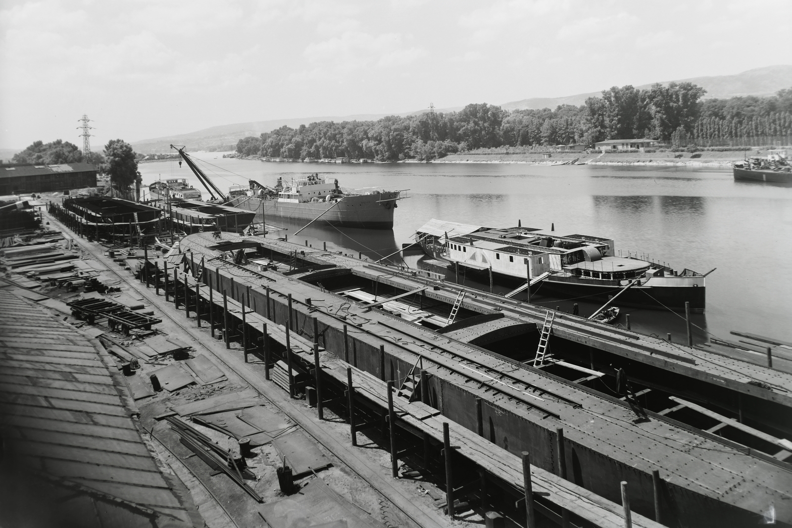 Hungary, Budapest XIII., Újpesti-öböl, Ganz és Tsa. Villamossági-, Gép-, Waggon- és Hajógyár Rt. Jobbra előtérben az épülő MFTR Verecke (1939), mögötte a DTRT Kassa (1939) Duna-tengerjáró áruszállító hajó, emögött az Újpest (1906) úszódaru. Leltári jelzet: MMKM TFGY 2017.1.420., 1939, Magyar Műszaki és Közlekedési Múzeum / Történeti Fényképek Gyűjteménye / Ganz gyűjtemény, Budapest, Fortepan #123117