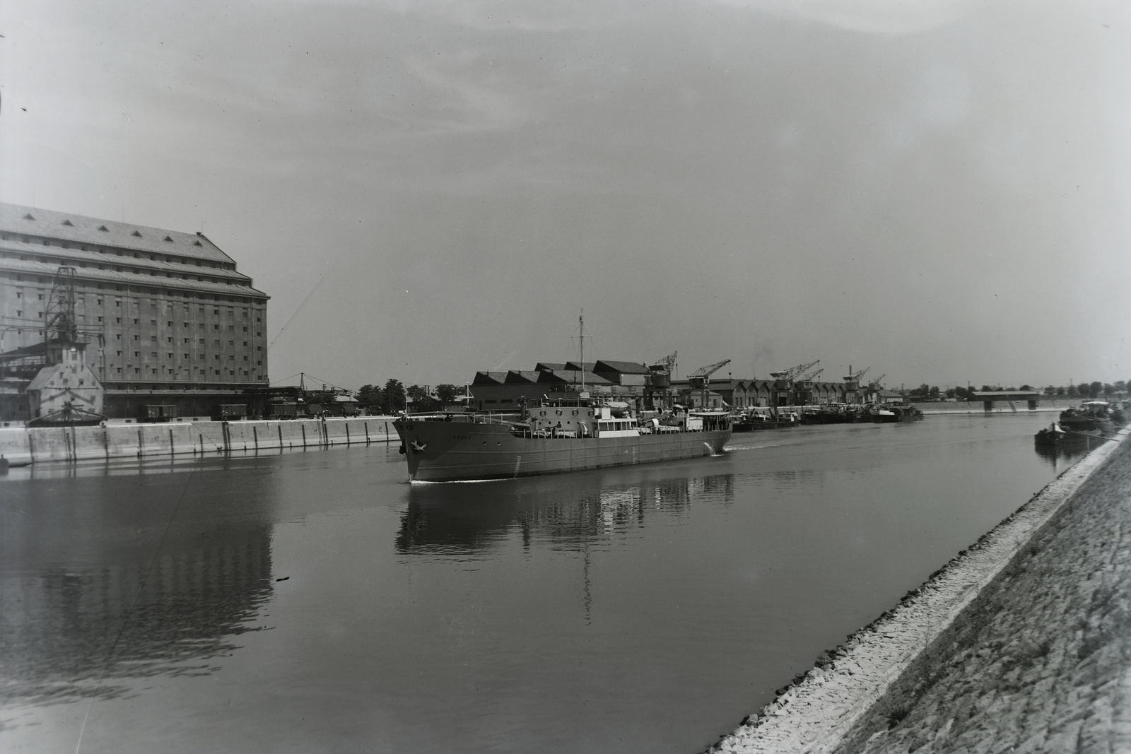 Hungary, Csepeli Szabadkikötő, Budapest XXI., DTRT Kassa (1939) duna-tengeri áruszállító csavaros motorhajó. Balra a Gabonatárház. Leltári jelzet: MMKM TFGY 2017.1.422., 1940, Magyar Műszaki és Közlekedési Múzeum / Történeti Fényképek Gyűjteménye / Ganz gyűjtemény, Budapest, Fortepan #123149