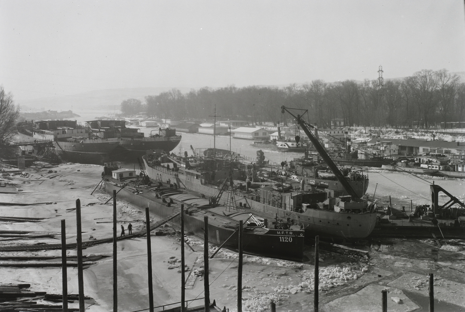 Magyarország, Budapest XIII., Újpesti-öböl, Ganz és Tsa. Villamossági-, Gép-, Waggon- és Hajógyár Rt., téli kikötő. A Magyar Vitéz (1942), Magyar Tengerész (1942), DTRT Szeged (1936), mögötte a Hunor (1937), illetve az Újpest (1906) úszódaru. Leltári jelzet: MMKM TFGY 2017.1.763., 1943, Magyar Műszaki és Közlekedési Múzeum / Történeti Fényképek Gyűjteménye / Ganz gyűjtemény, úszódaru, Budapest, Fortepan #123172