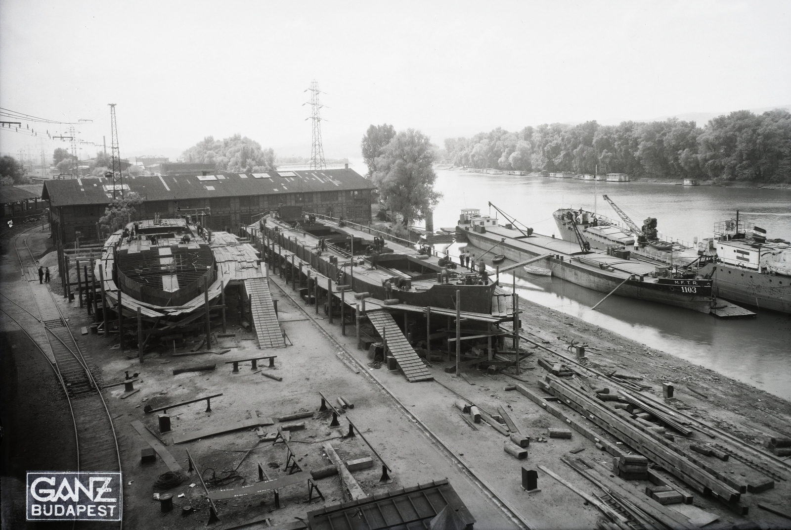 Hungary, Budapest XIII., Újpesti-öböl, a Ganz és Tsa. Villamossági-, Gép-, Waggon- és Hajógyár Rt. Épülő hajók a sólyán, jobbra egy 1000 tonnás áruszállító uszály. A vizen jobbra a DTRT Szeged (1936) Duna-tengerjáró áruszállító motorhajó. Leltári jelzet: MMKM TFGY 2017.1.472., 1940, Magyar Műszaki és Közlekedési Múzeum / Történeti Fényképek Gyűjteménye / Ganz gyűjtemény, barge, Budapest, Fortepan #123191